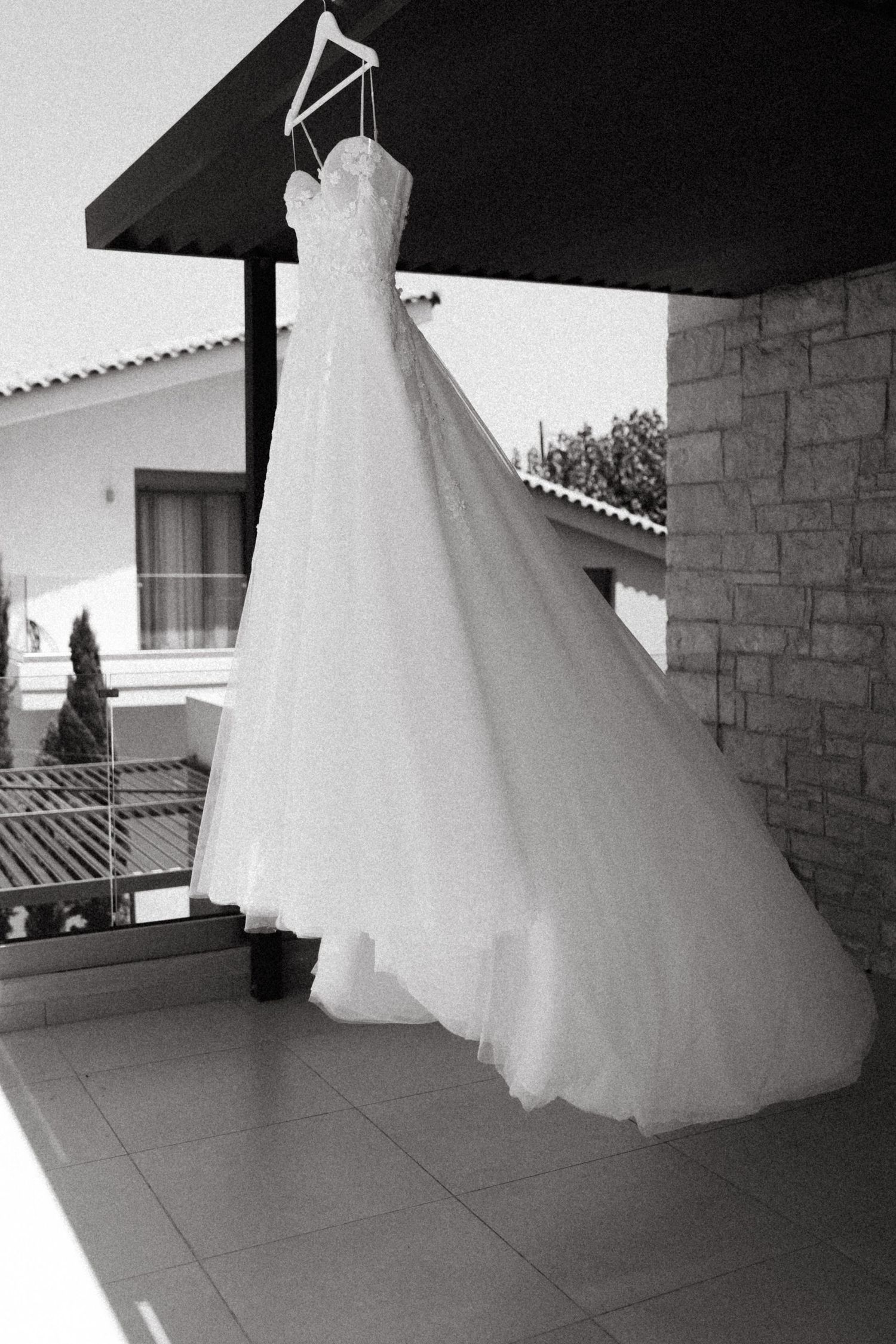 White wedding dress hangs elegantly against stone wall architecture.