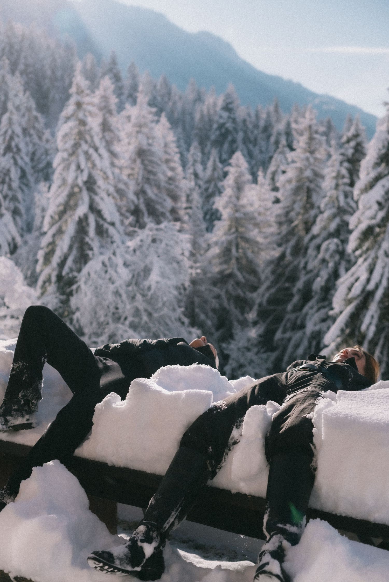 Candid alpine moment: person resting on a snow-covered bench with panoramic views of the French Alps. Content creation by studio Reverie
