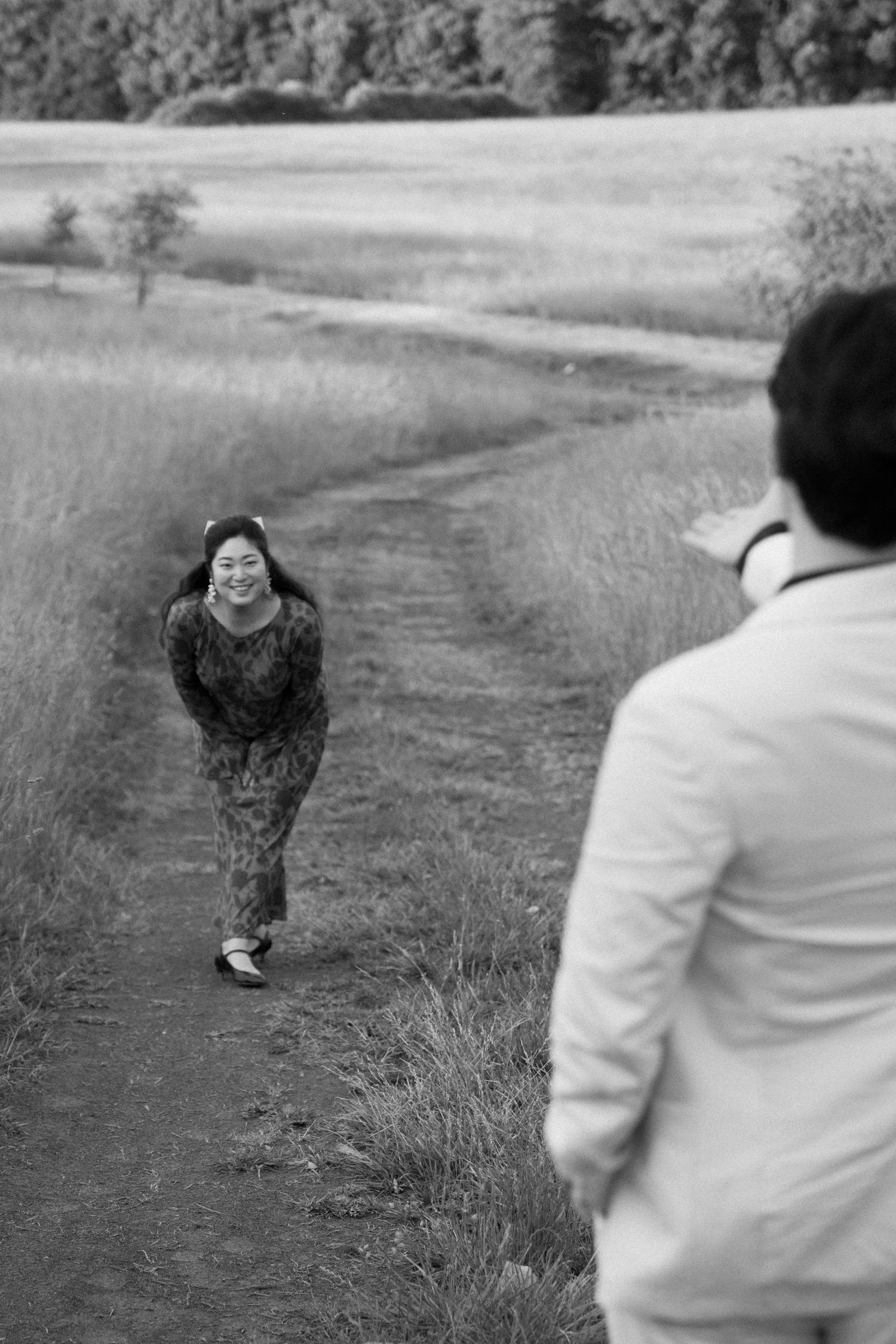 A black and white photo of two people meeting on a countryside path.