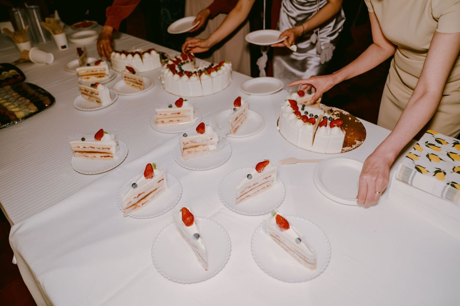 White tablecloth setting with partially visible dessert plates topped with strawberries being served.