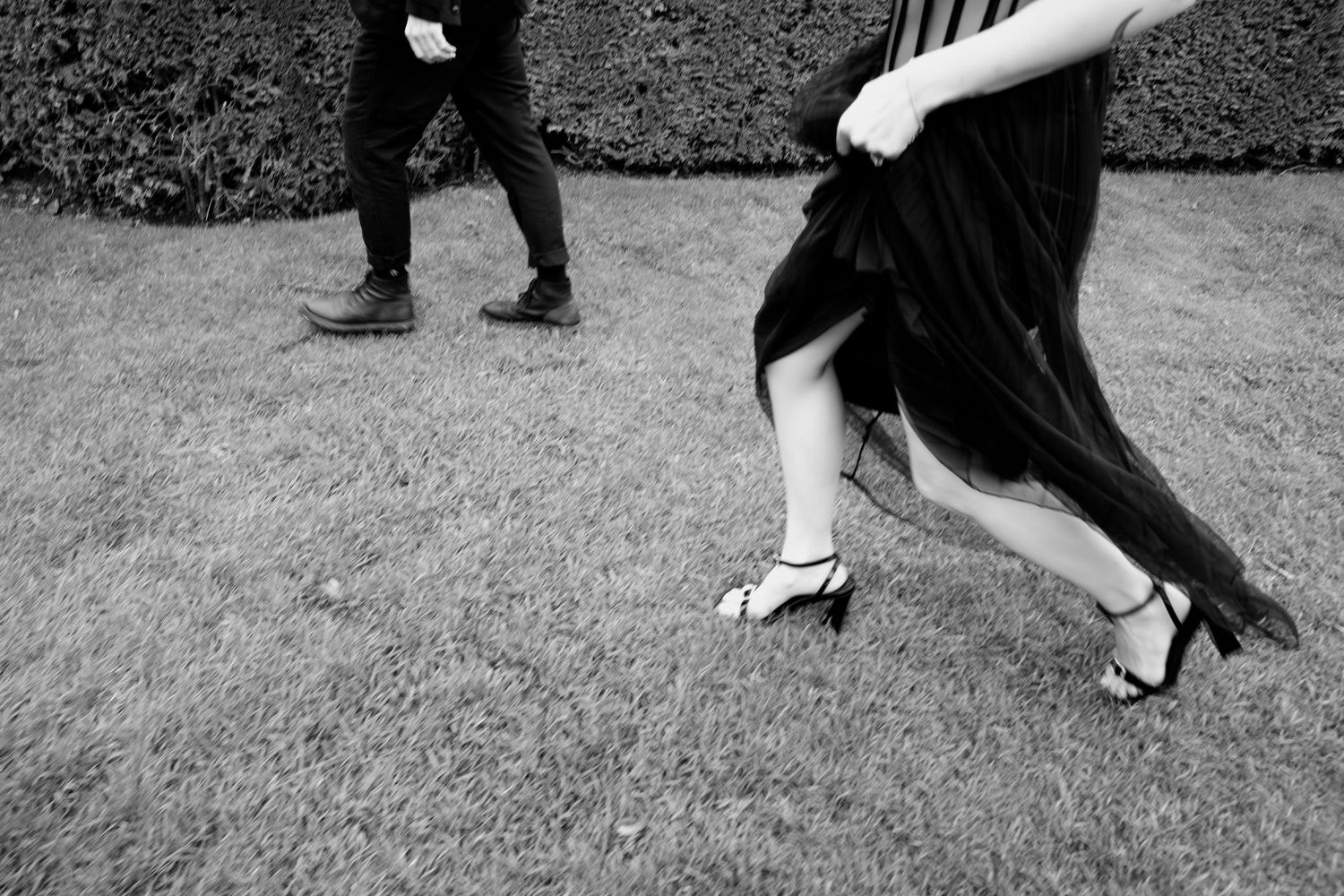 Detail shot of a couple running through Louvre gardens in black dress and heels, cinematic Paris editorial shoot by Studio Reverie.