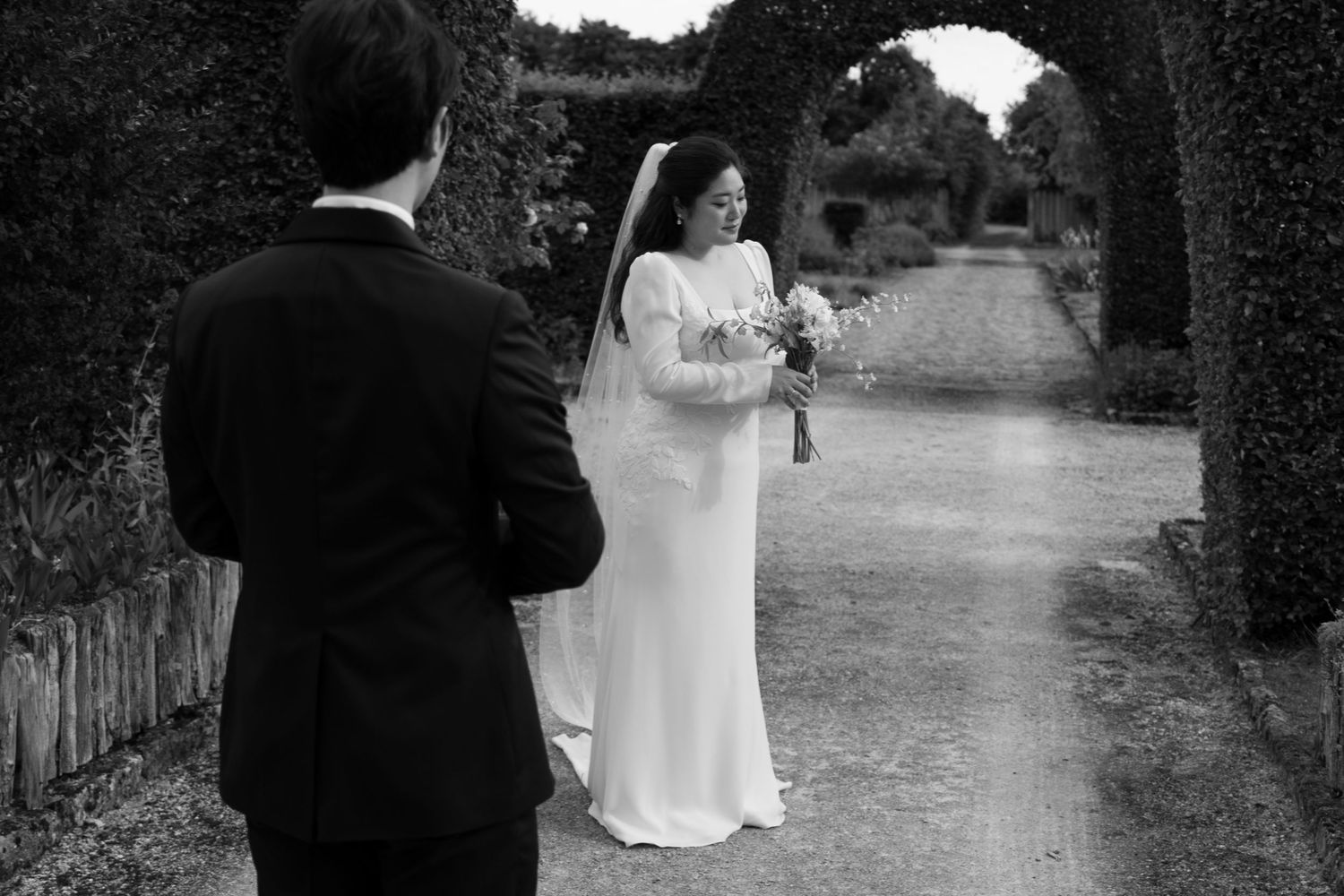 A black and white wedding photo collage showing intimate moments between a couple walking along a garden path.