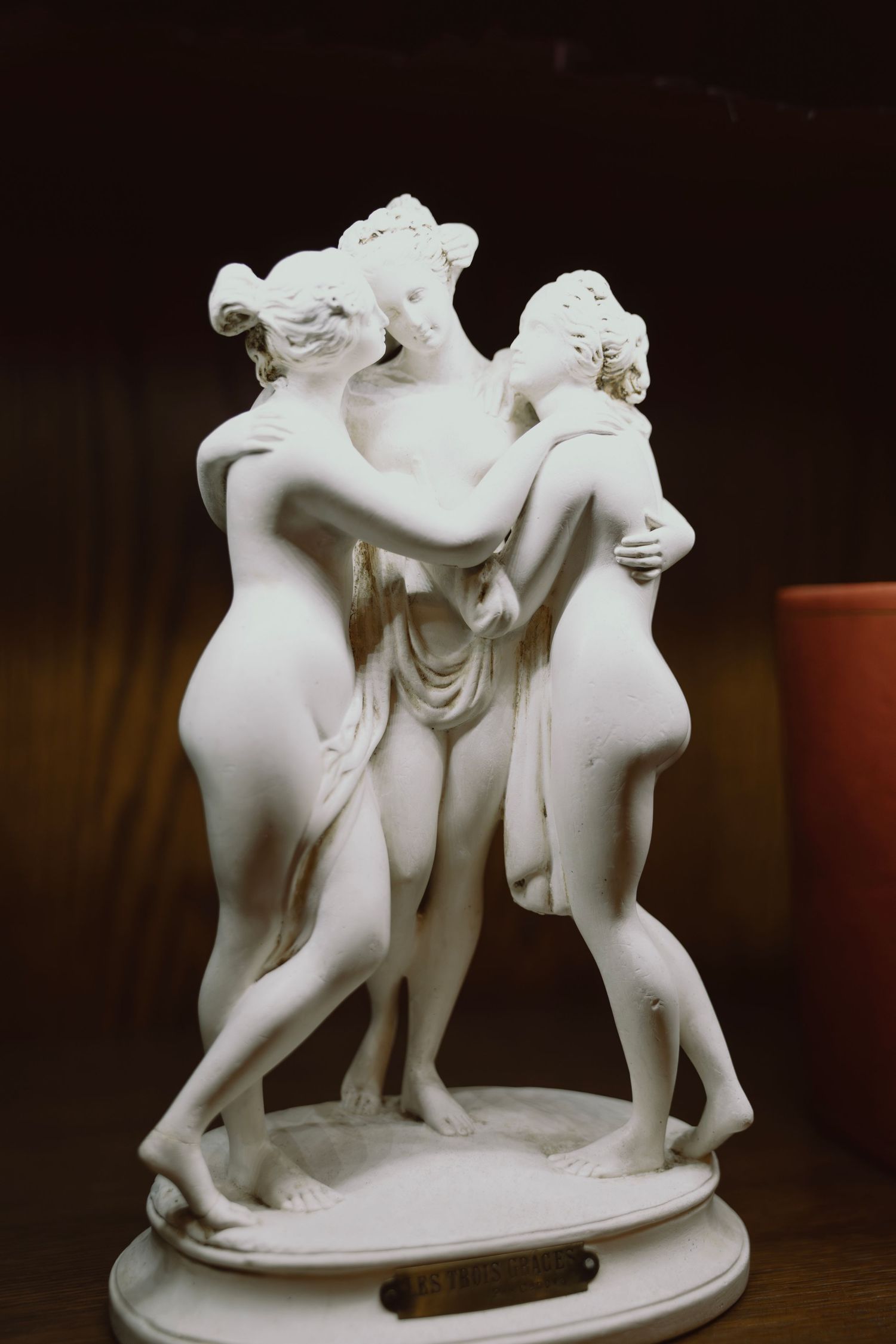 Classical white porcelain sculpture depicting three graceful figures in an intimate pose.