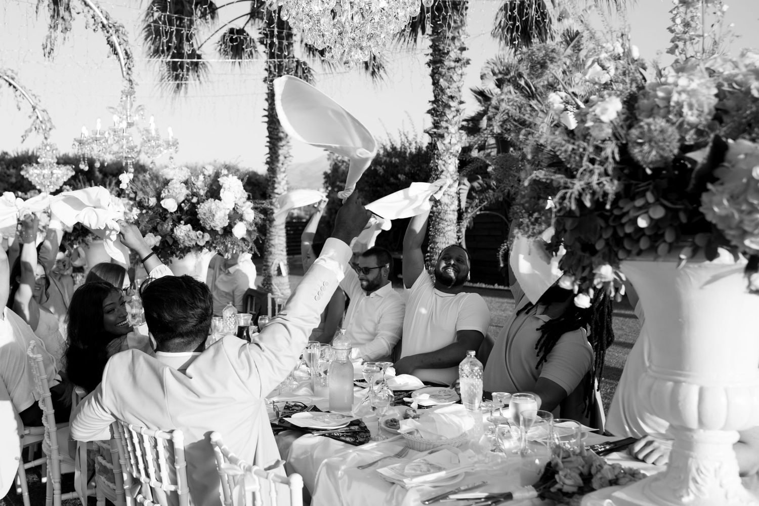 A large crowd gathers outdoors for a festive celebration with decorations and tents visible in the background.