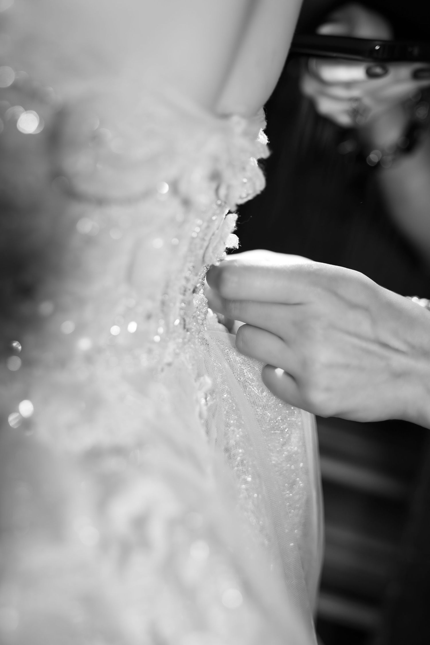 Close-up detail of intricate beadwork and lace on a white wedding dress.