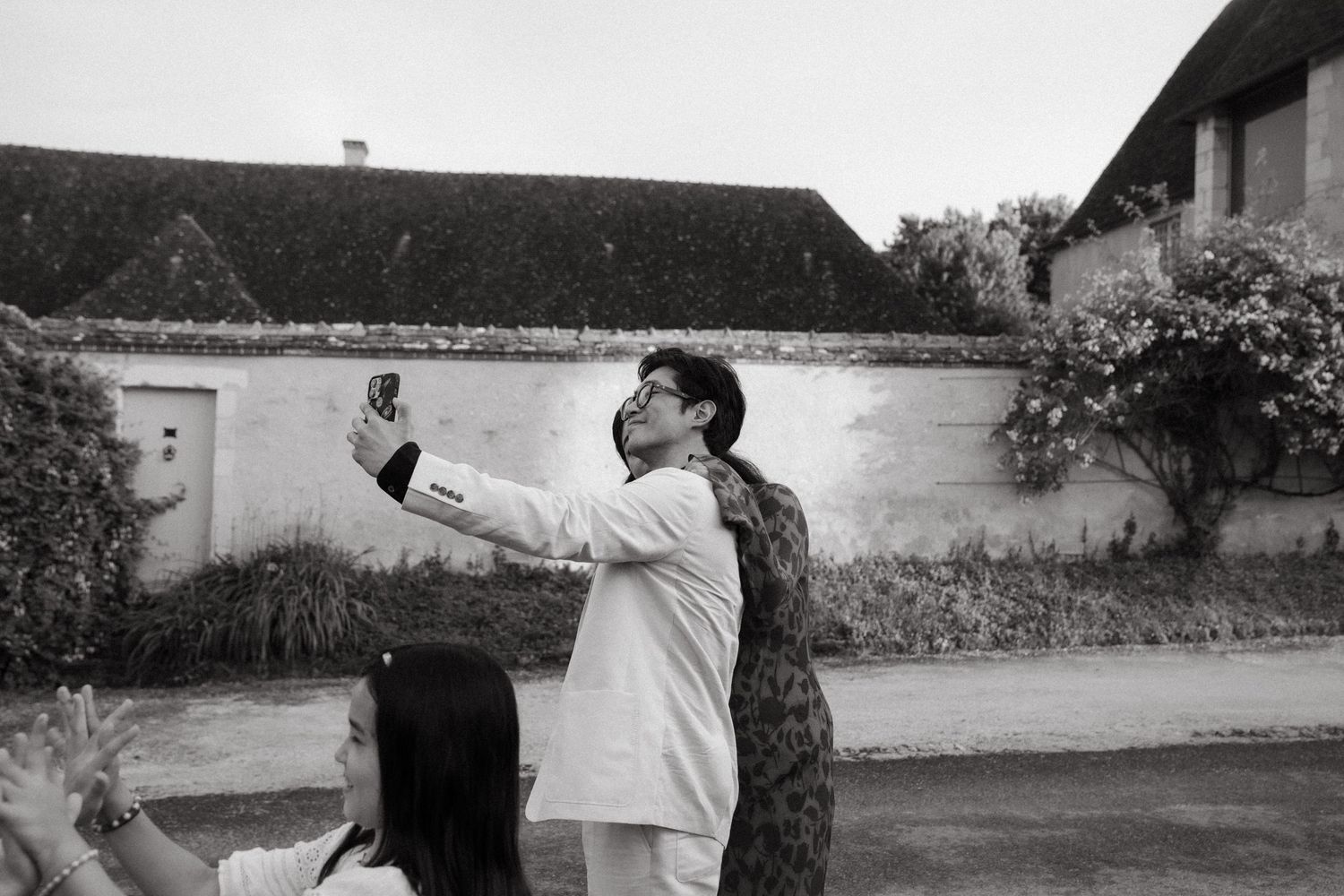 A couple takes a selfie together in front of a garden wall.