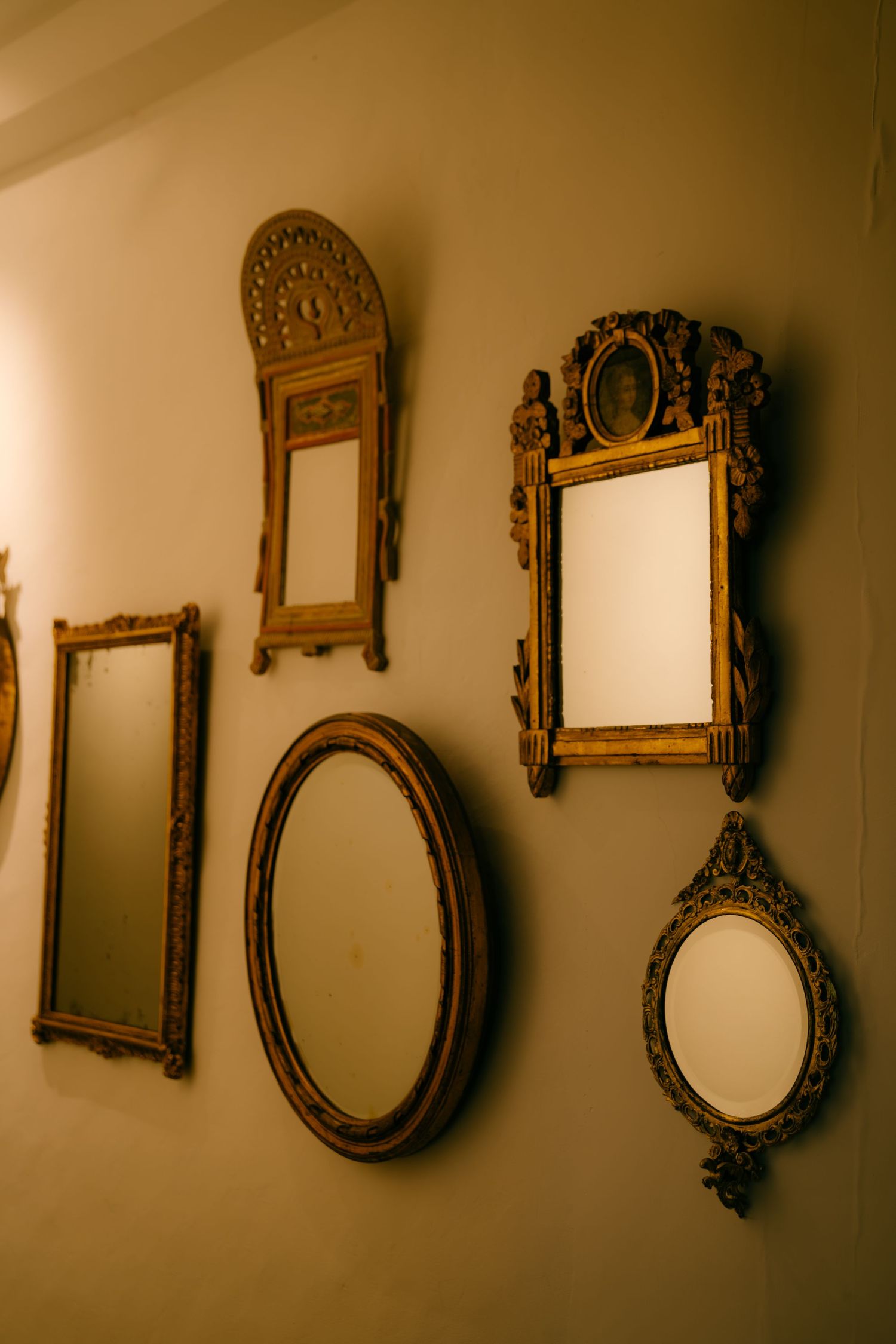 Collection of ornate vintage gold mirrors arranged in a row on a neutral wall creating an artistic display.
