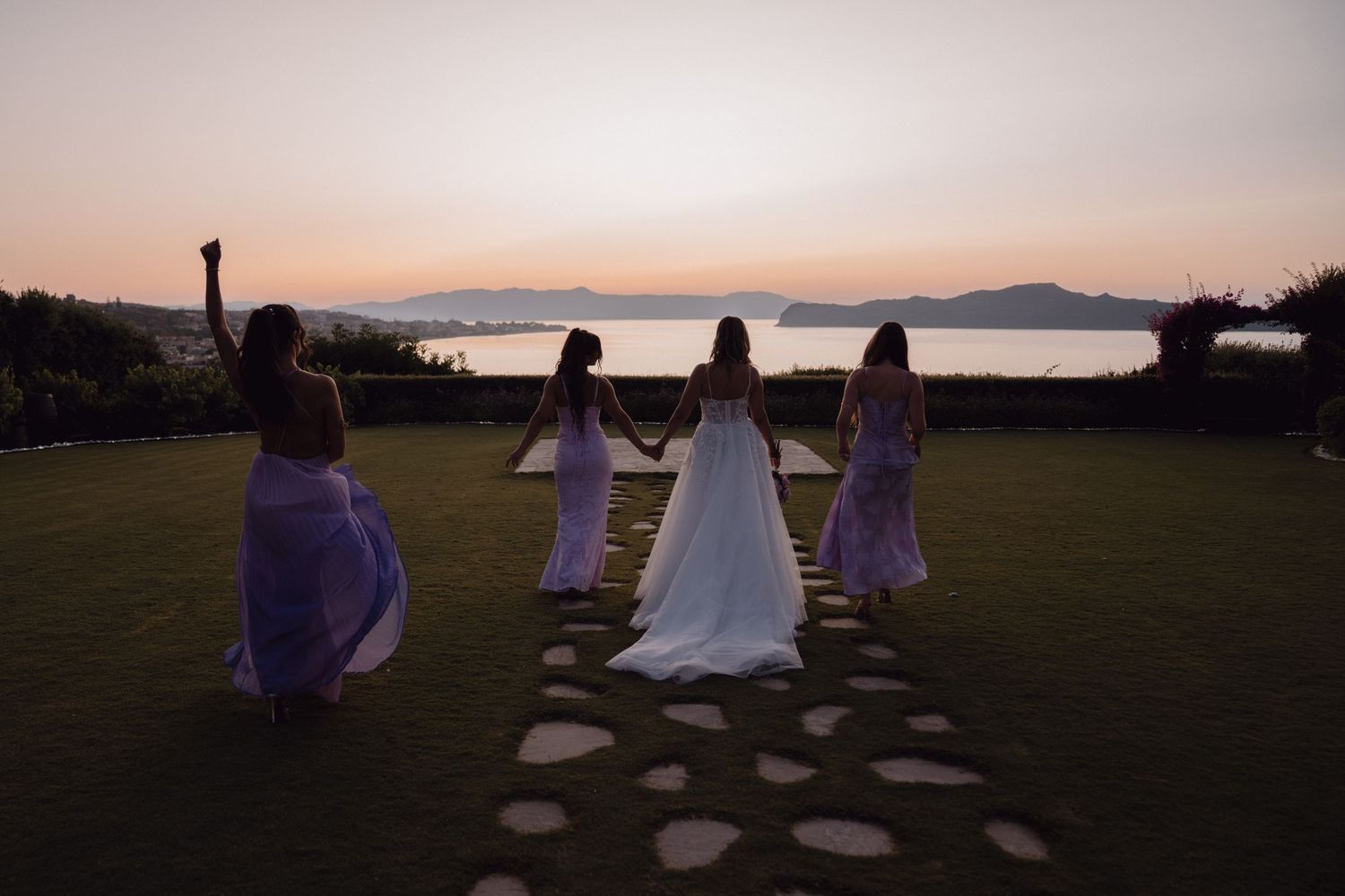People sitting on blankets watching a scenic sunset over mountains and water.