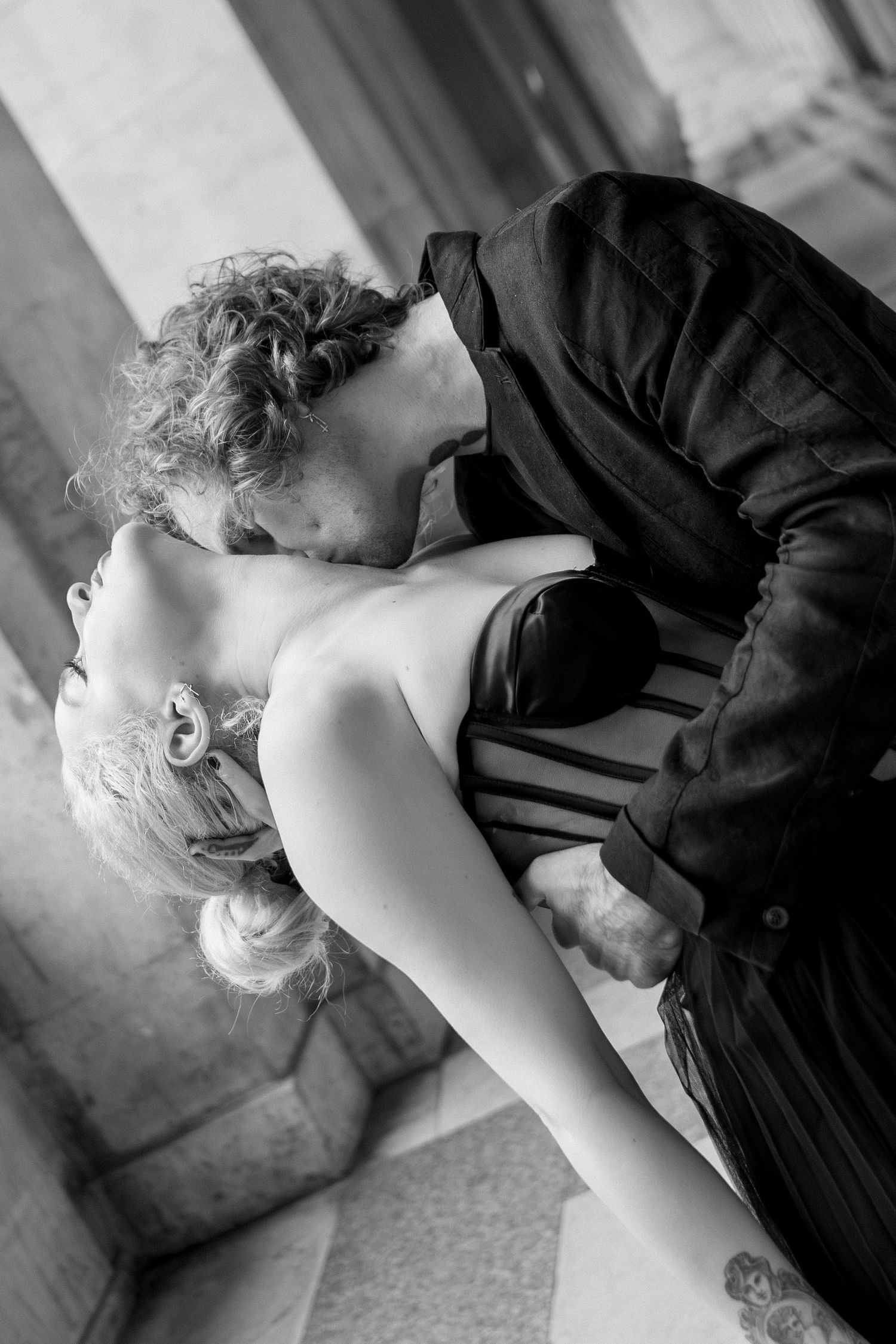 Editorial couple kissing at the Louvre in Paris, dramatic black and white fashion-inspired photography by Studio Reverie.