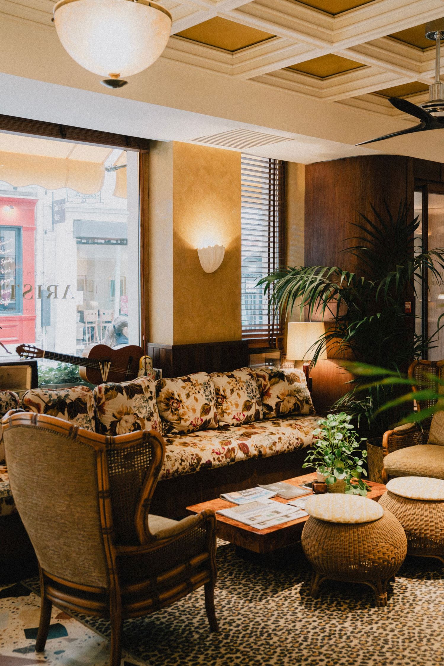 Elegant hotel lounge with floral pattern sofas, palm plants, and warm lighting creating a luxurious seating area.
