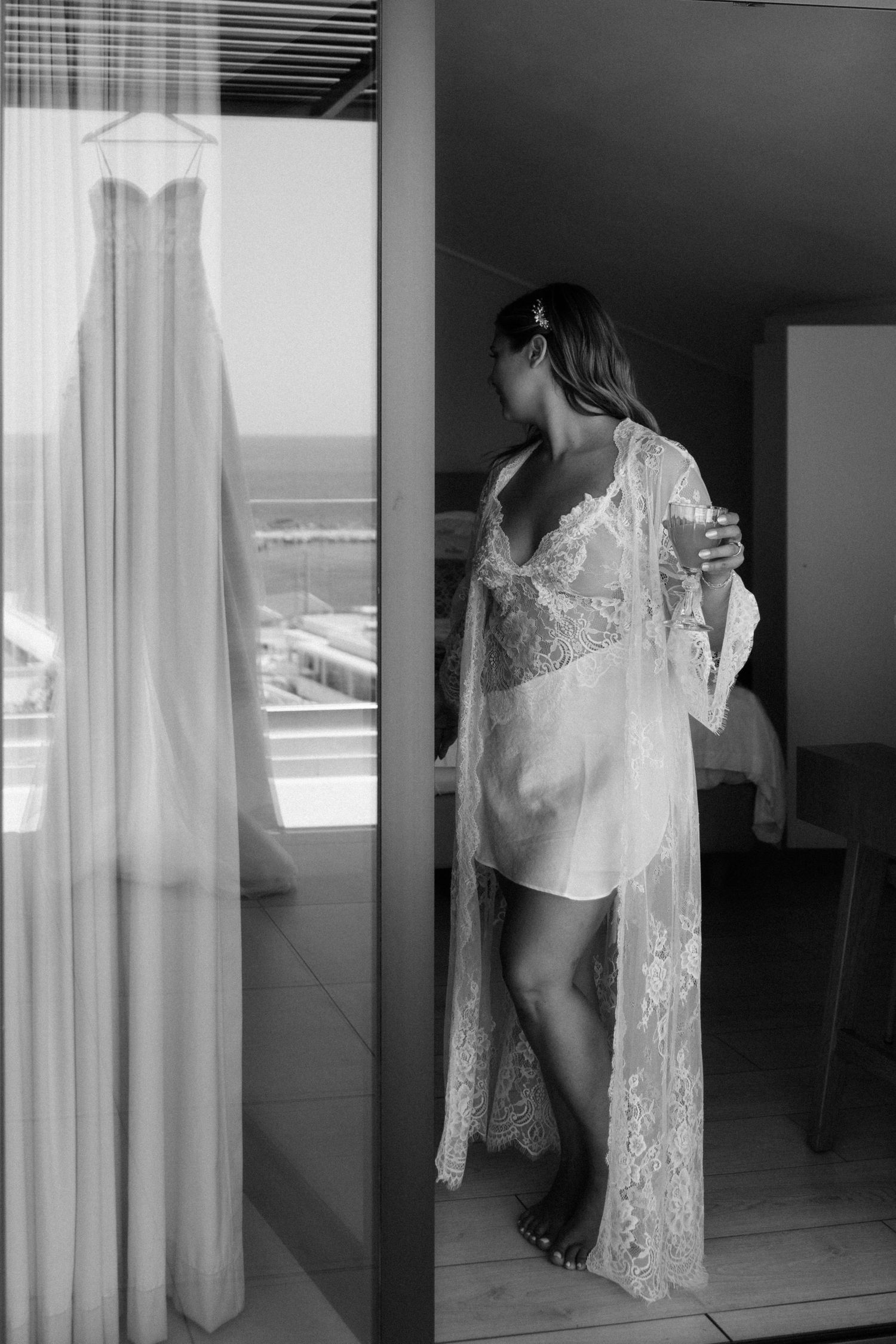 A series of white wedding dresses and bridal gowns displayed in a dark room against a window with natural light.