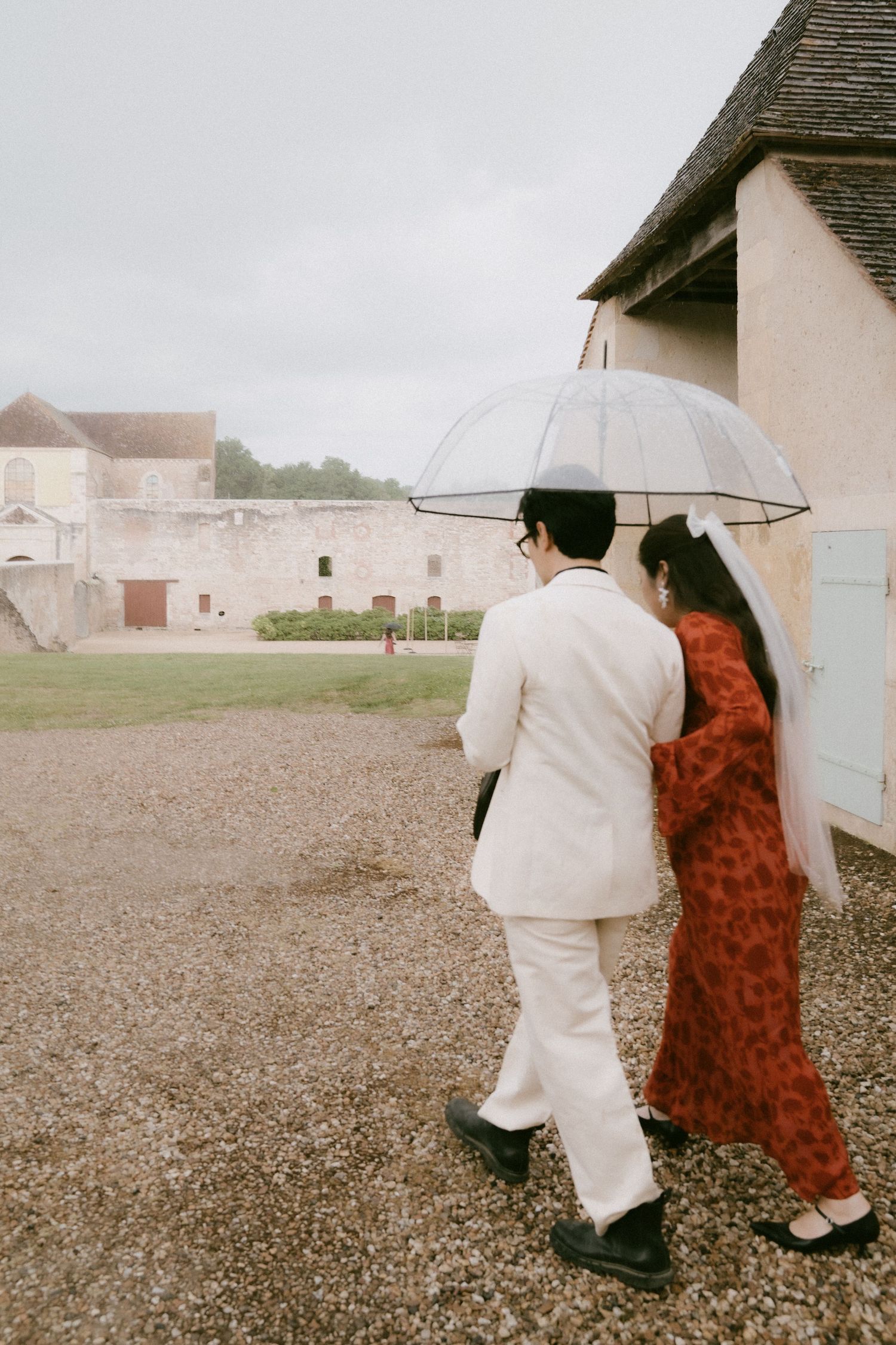 Artistic sequence showing two people walking with umbrellas against a rustic farmhouse backdrop.