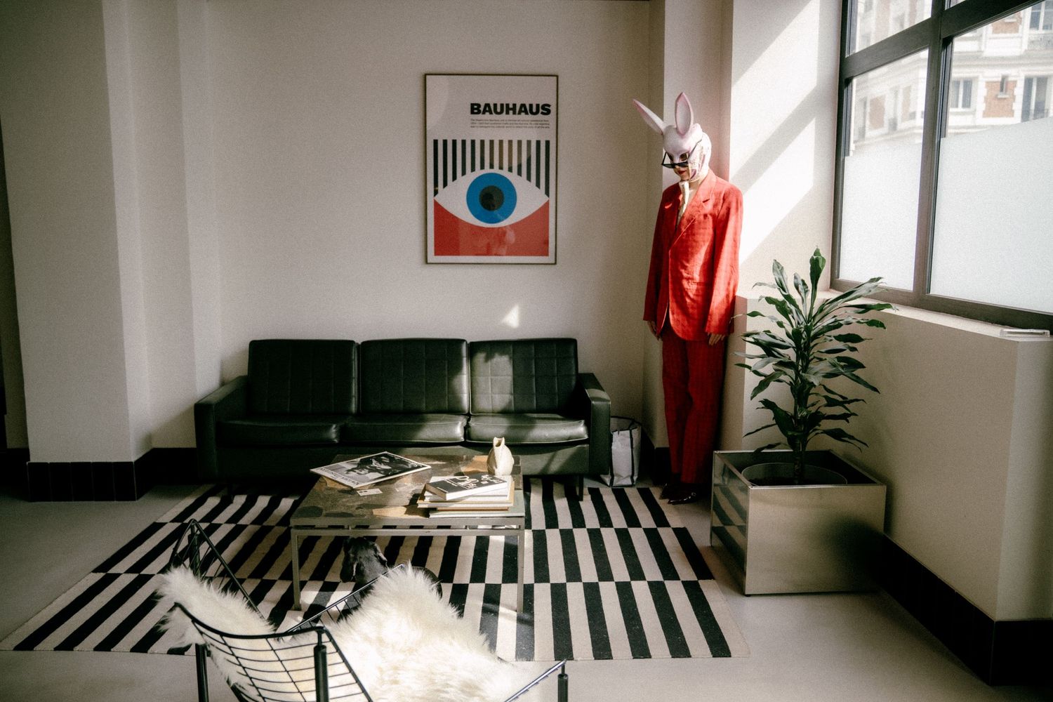 Paris fashion editorial scene with retro decor, model in bold red suit beside modernist art in natural window light. Photo by Studio Reverie