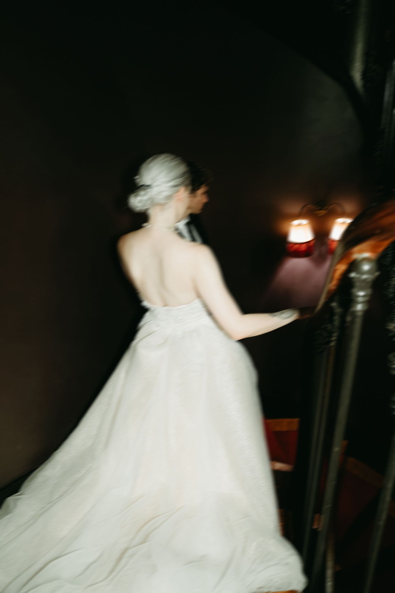 Motion-blurred shot of flowing white wedding gown in dark setting.