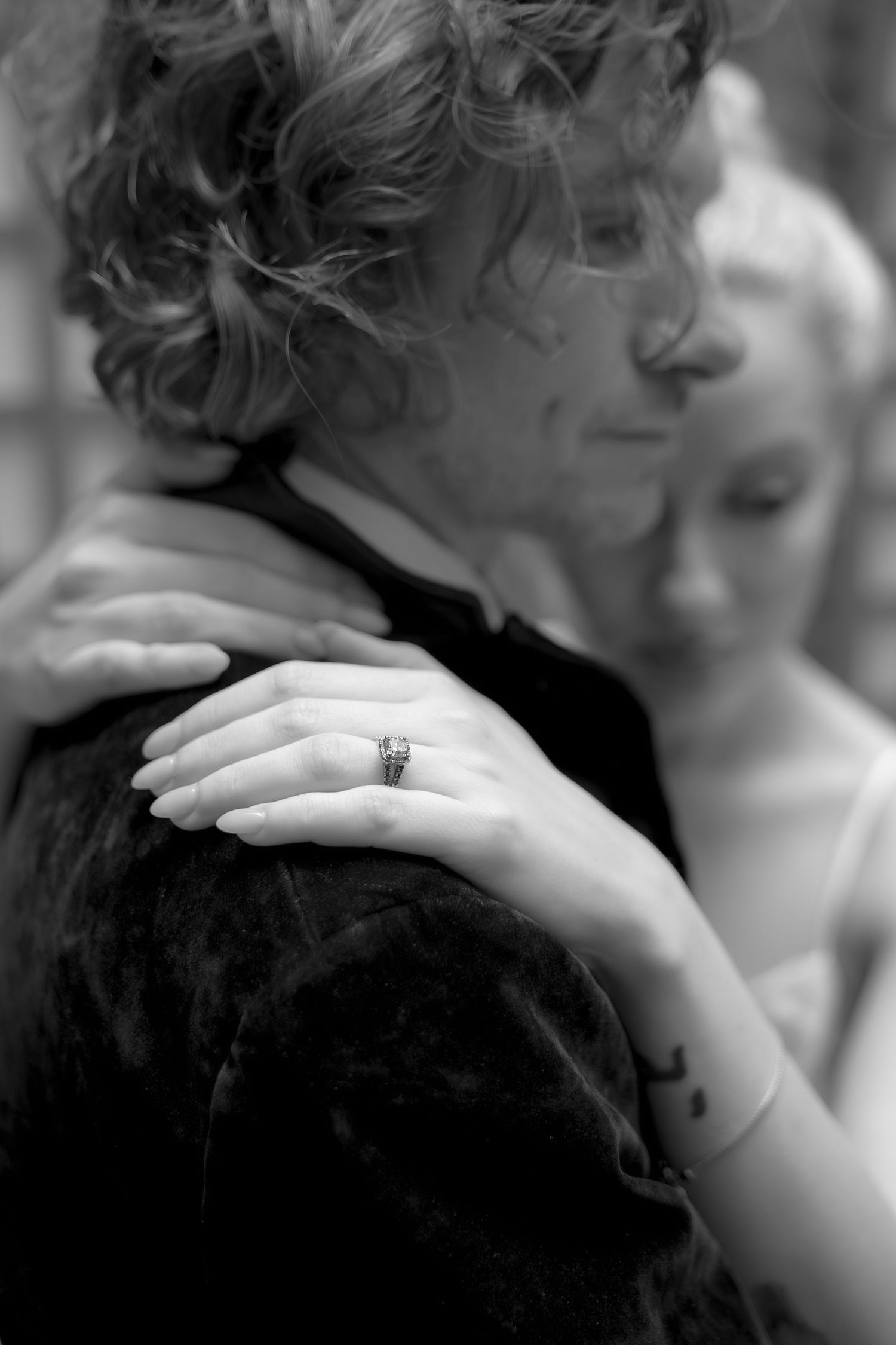 Close-up black and white photo of hands and curly hair in an intimate moment.