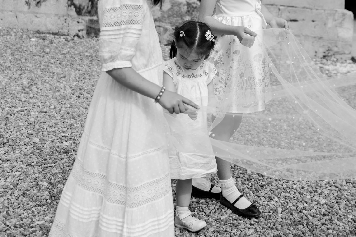 Children in white dresses playing outdoors during a wedding celebration.