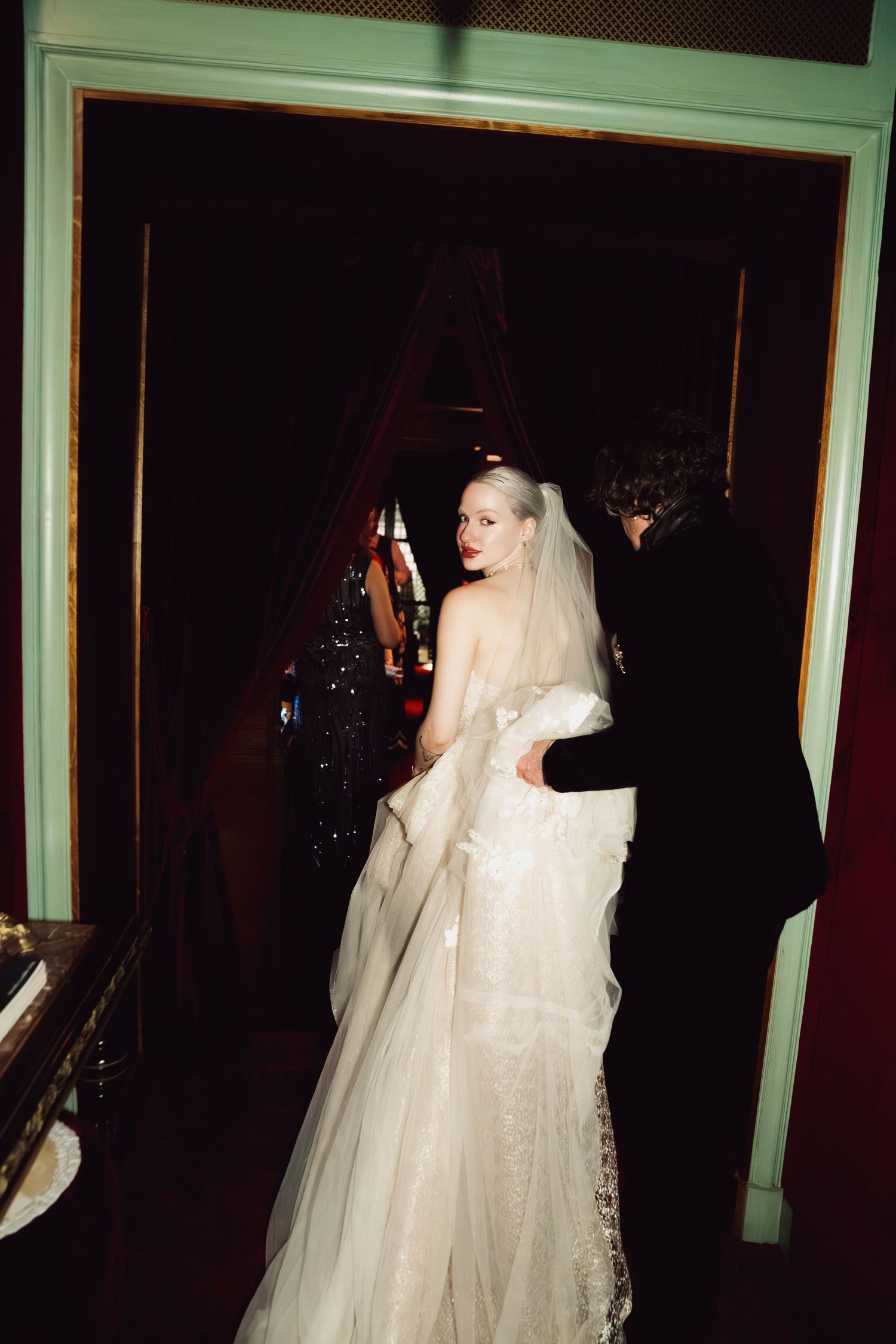 Dramatic nighttime wedding photo with white dress against dark background.