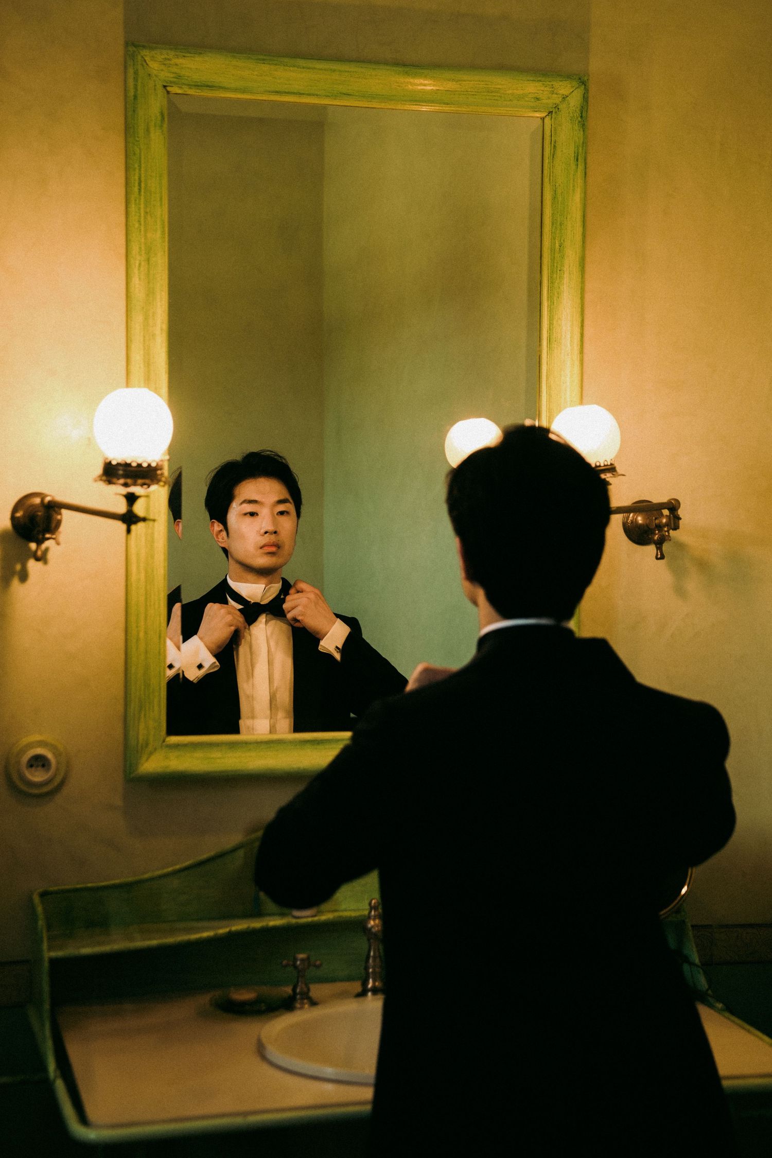 Moody bathroom mirror sequence showing a figure taking photos in dim lighting.