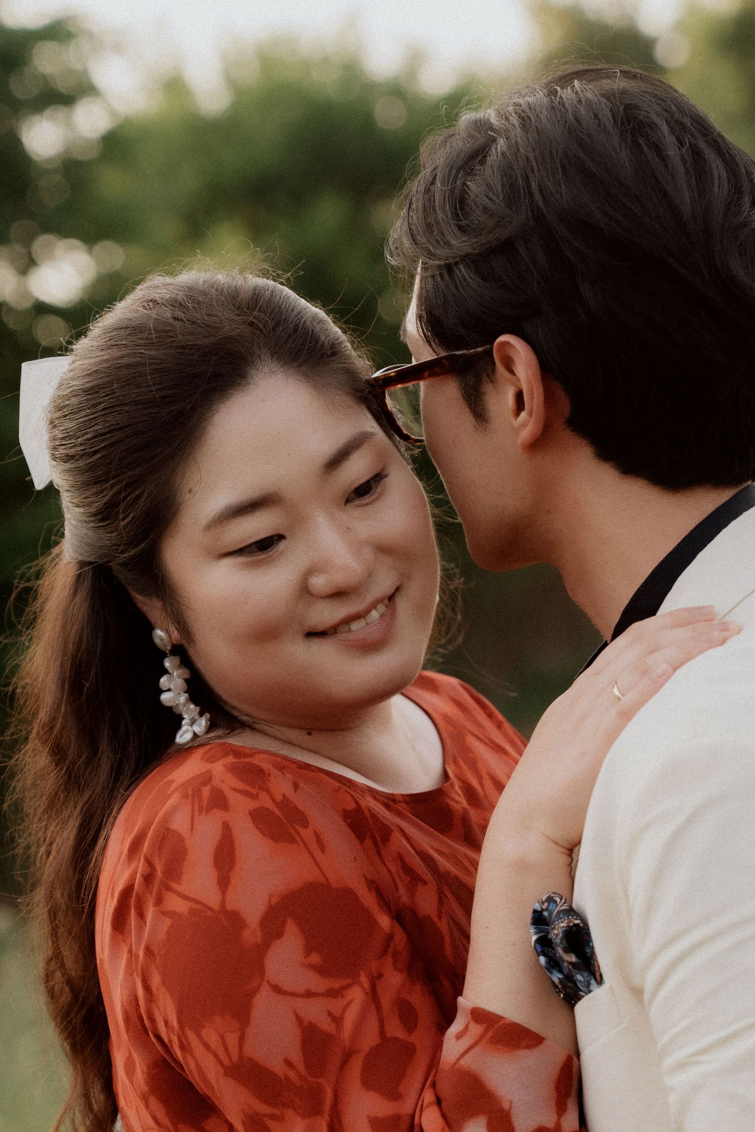 A couple shares an intimate moment during sunset in a garden setting.