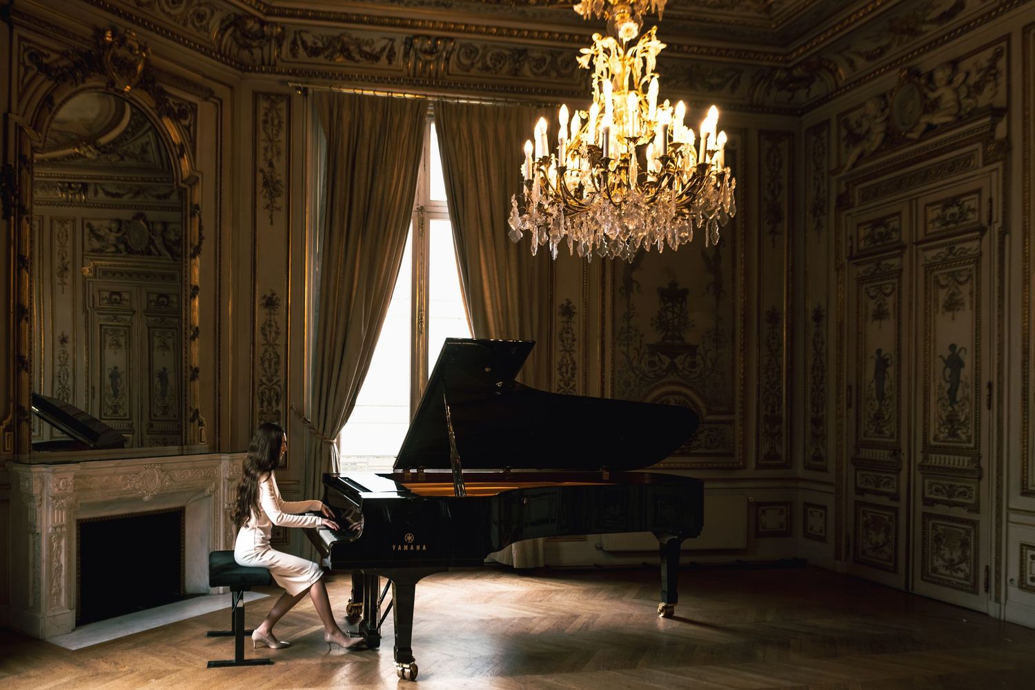 Paris couple shoot in a historic room with chandelier and piano, unposed and naturally cinematic moment