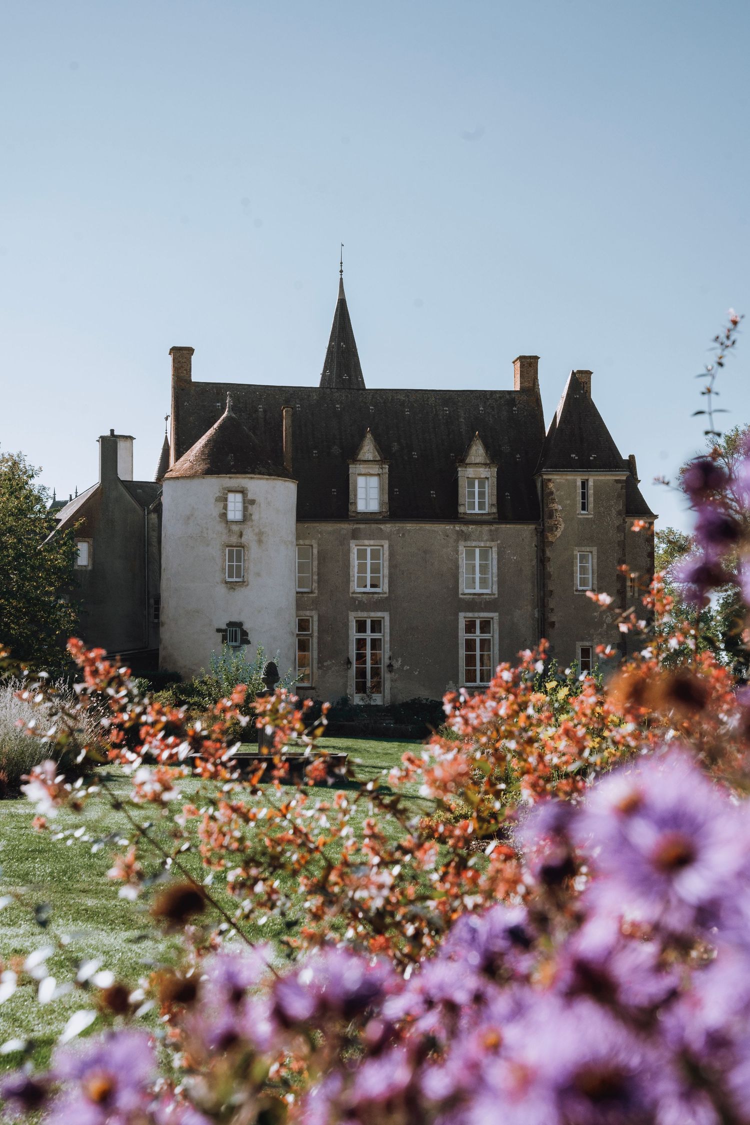Historic stone castle with pointed spires photographed through colorful spring flowers in the foreground.
