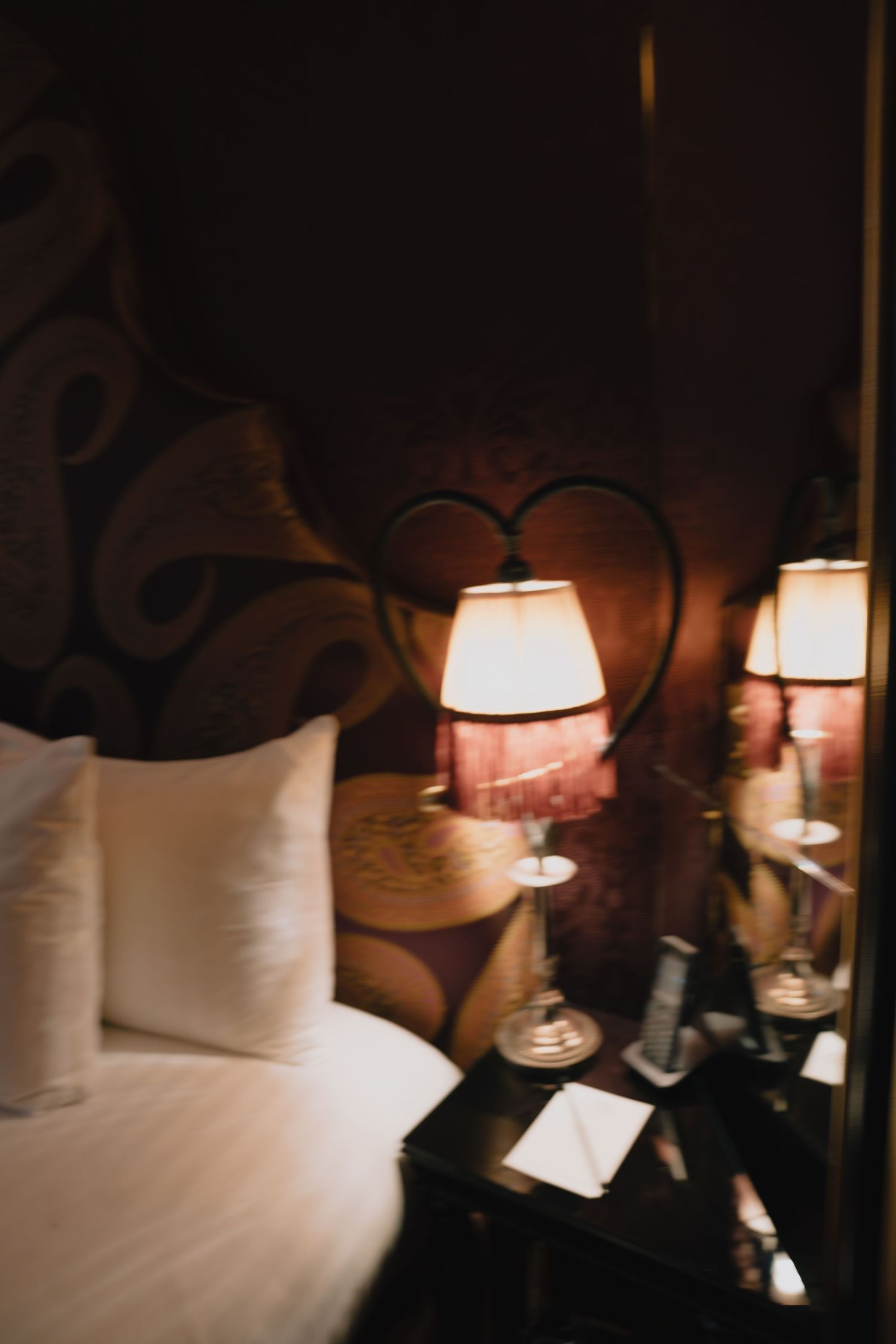 A cozy hotel room interior with white bedding and glowing table lamps creating warm ambient lighting.