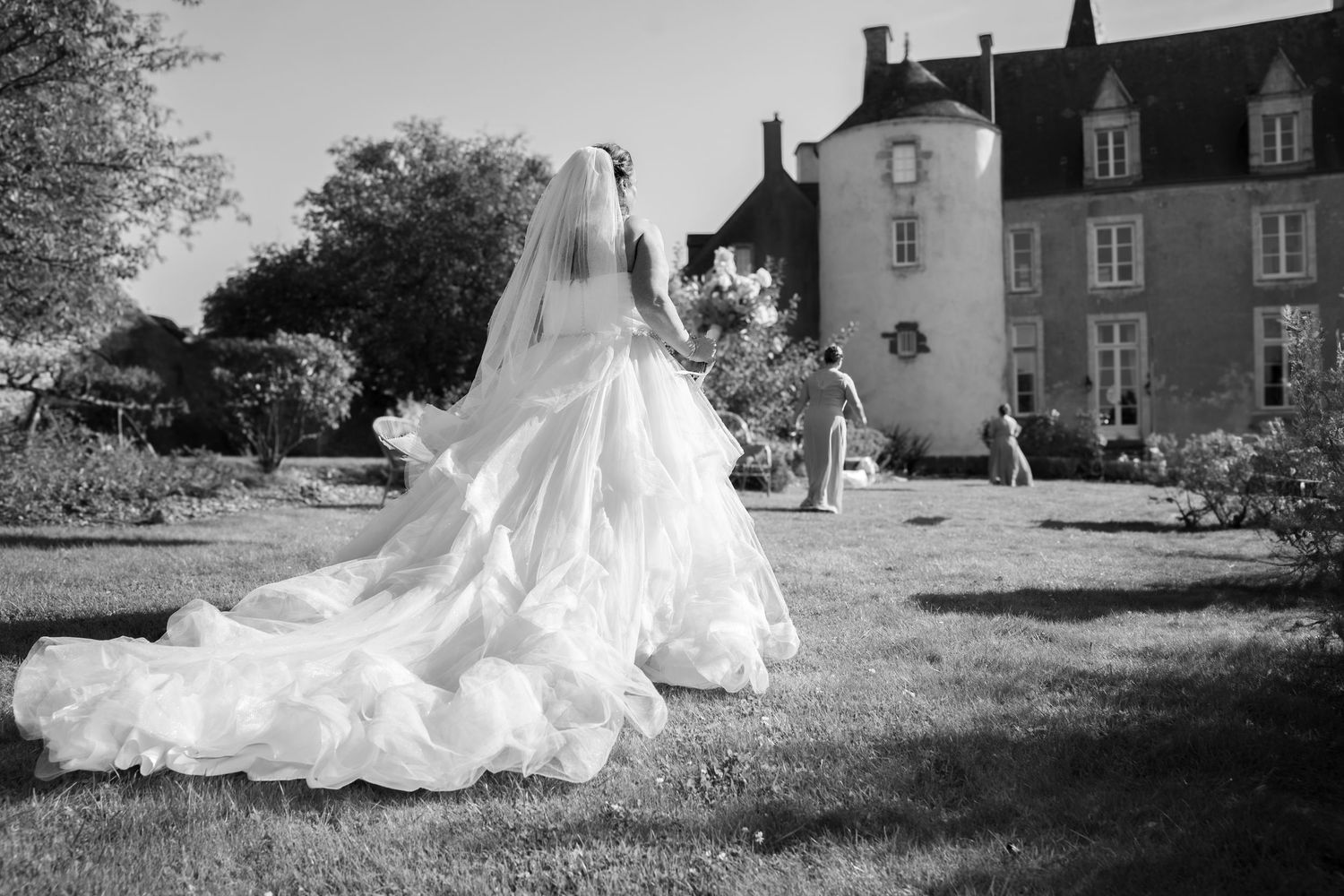 A series of black and white wedding photos showing a bride in a flowing white dress posing outdoors near historic buildings.