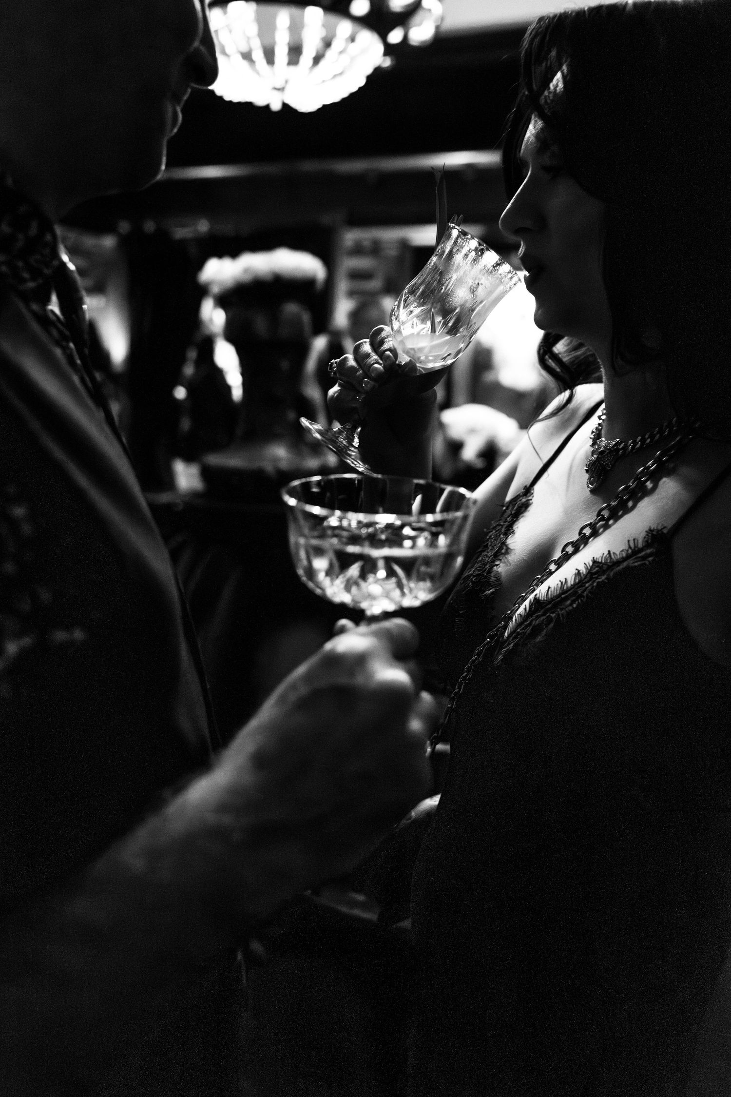 Atmospheric black and white photo of champagne glasses in dim lighting.