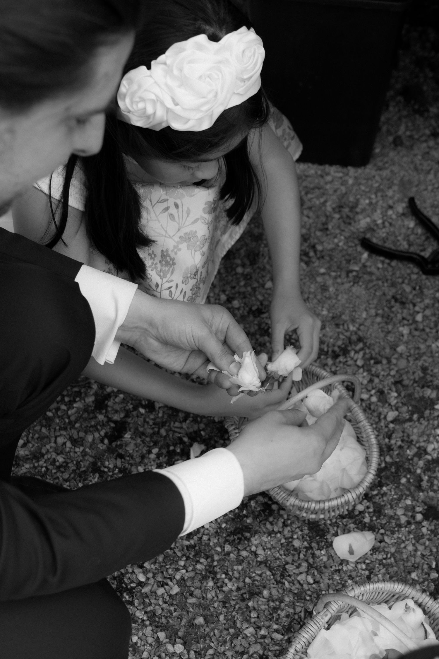 Black and white close-up of hands cutting a wedding cake with traditional cake serving set.