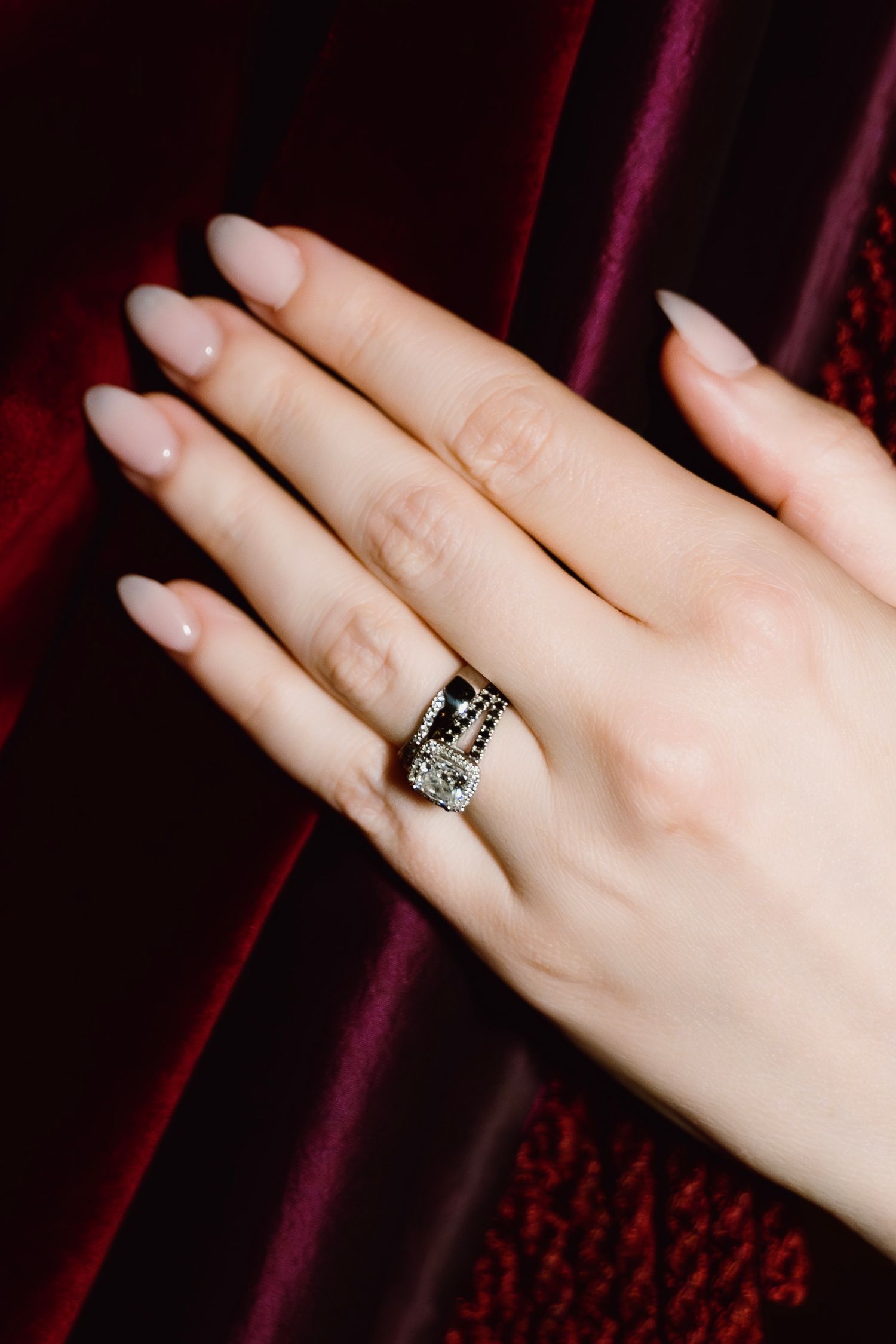 Close-up of an elegant vintage-style engagement ring against burgundy velvet.