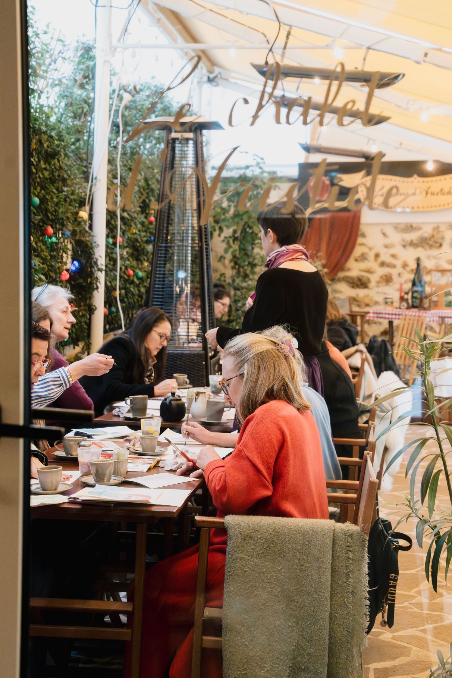 Diners enjoy a meal at a restaurant with stone walls and outdoor seating under an awning.