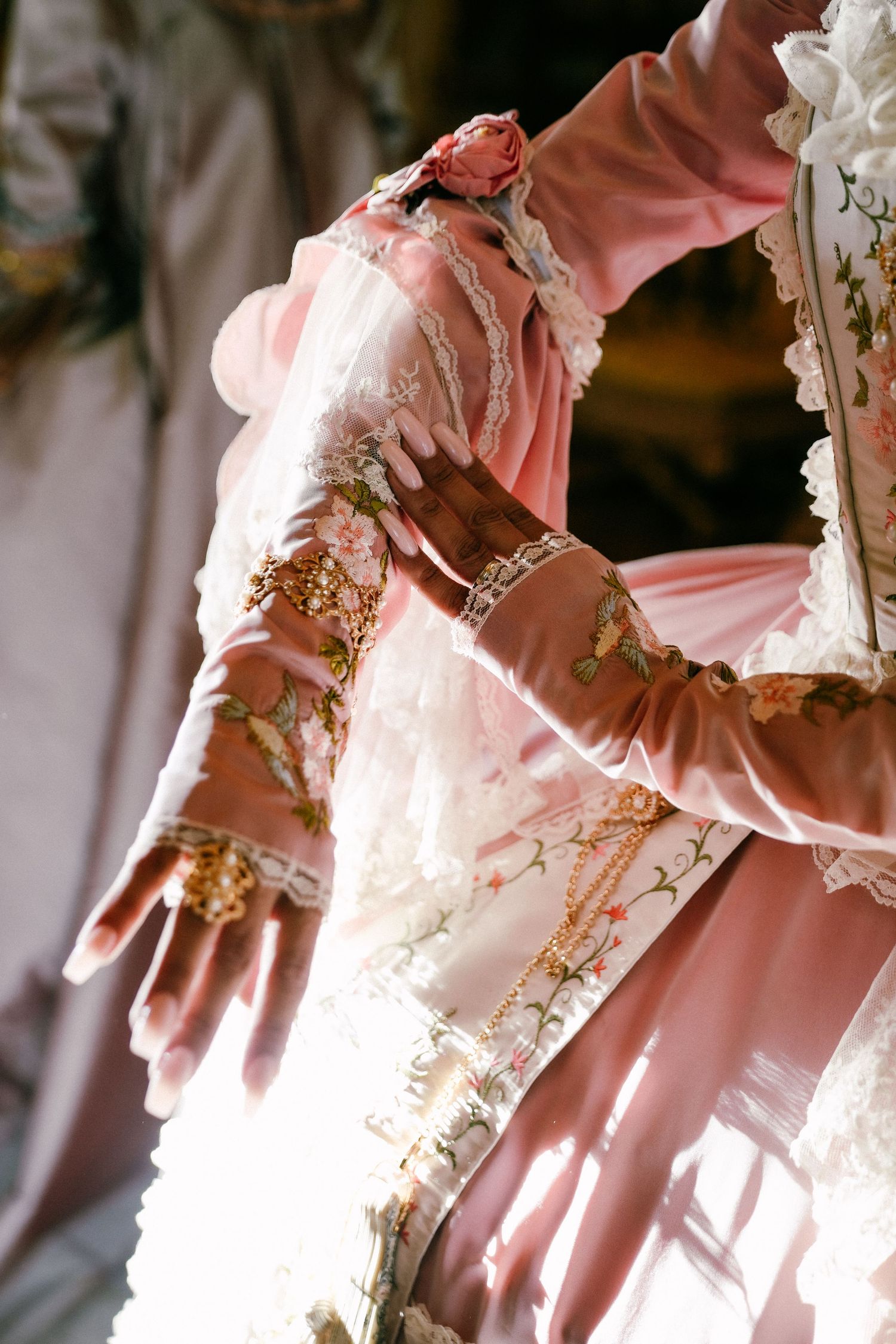 Elegant pink and white lace Victorian-style dress details with delicate ruffles and ornate embellishments.