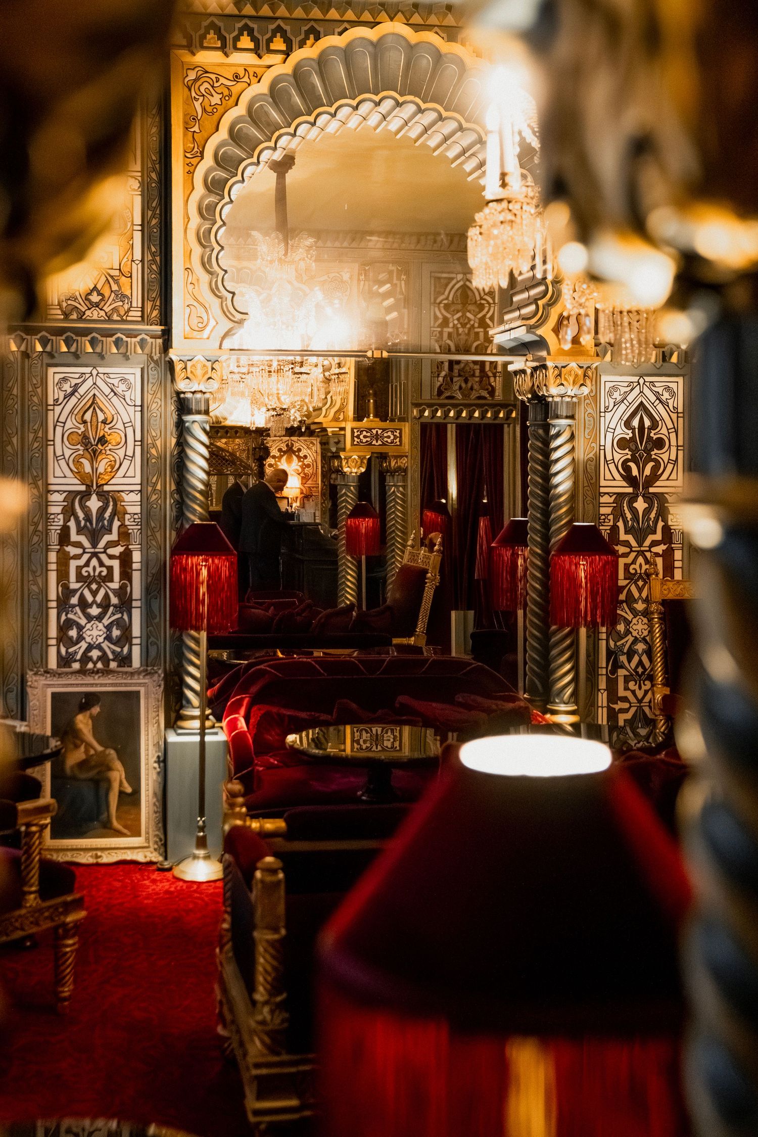 Ornate theater interior with gothic arches, red velvet seating, and decorative gold trim illuminated by warm lighting.