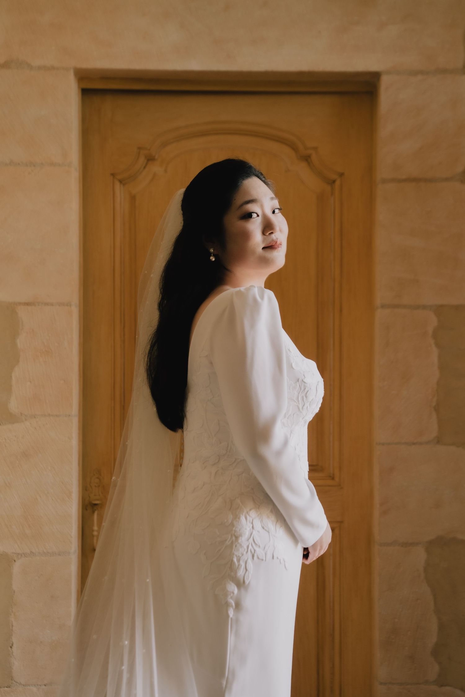A sequence of artistic bridal portraits in white against a neutral stone wall with wooden doors.