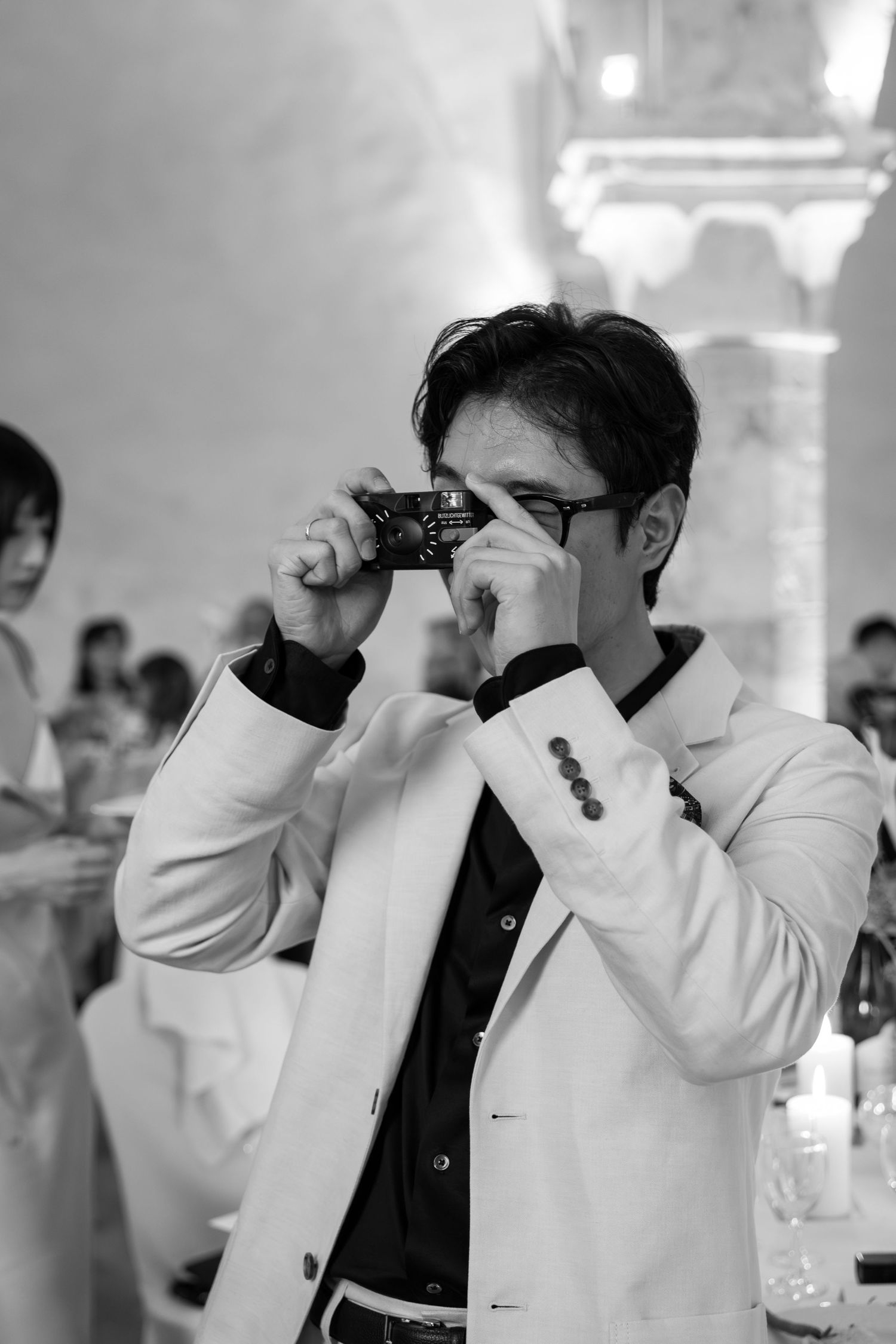 Black and white wedding photos show emotional moments during a celebration in an indoor venue.