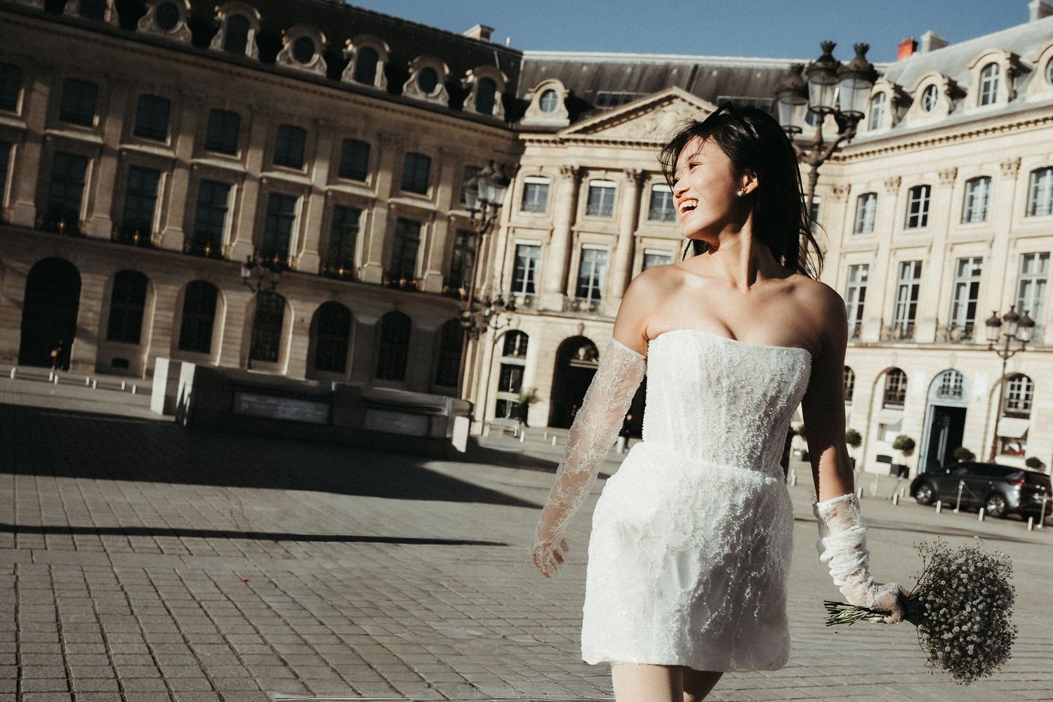 Couple dances and twirls in front of grand historic building during wedding shoot.