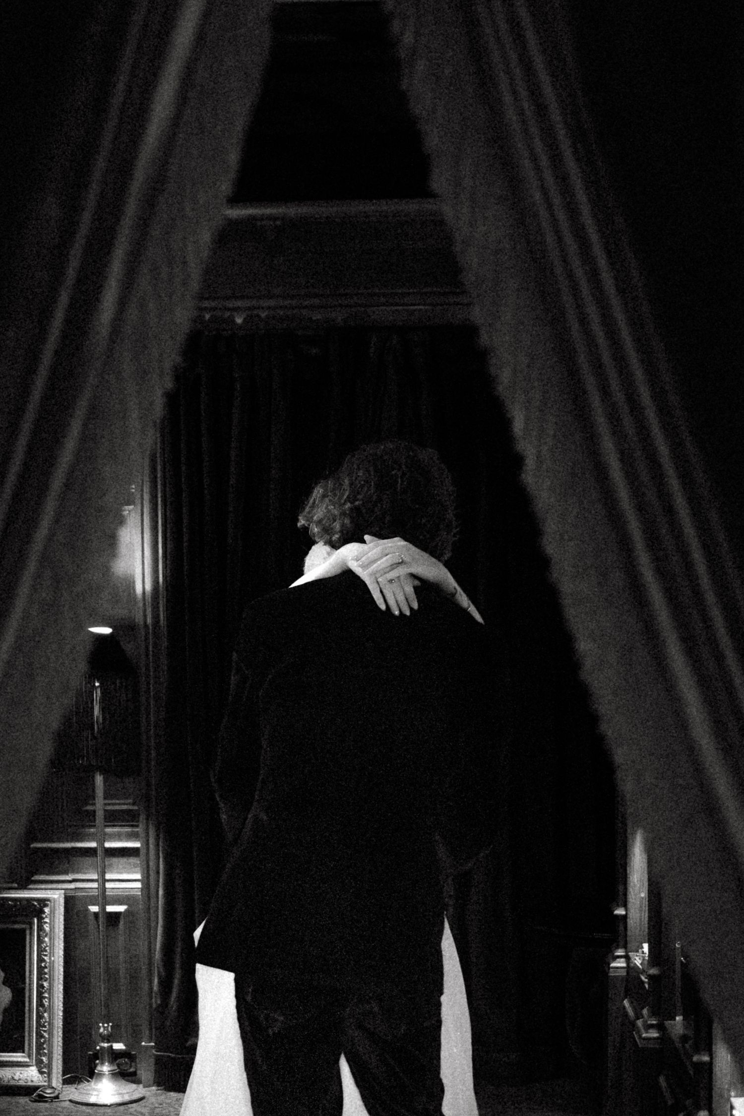 Silhouette of formal attire against window light in a dark room with curtains.
