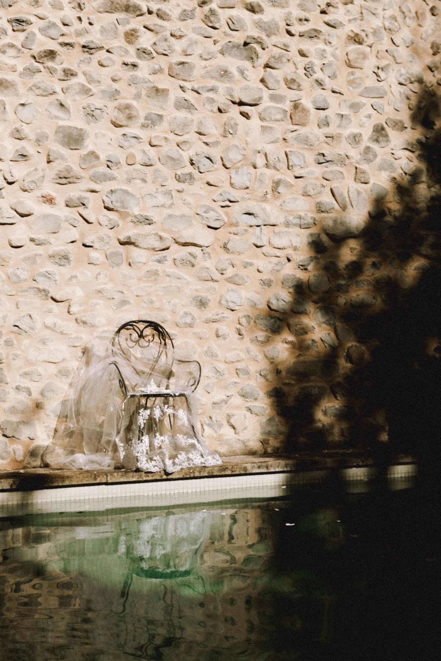Vintage stone wall with decorative glass vessels creating elegant shadows.