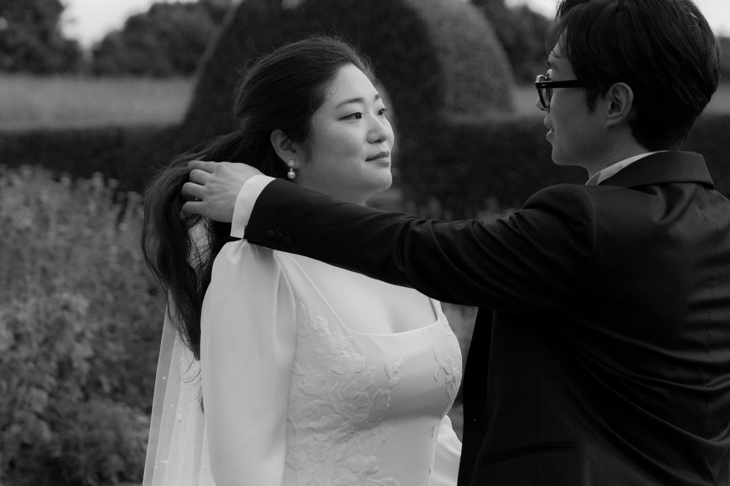 A black and white wedding photo collage showing intimate moments between a bride and groom outdoors.