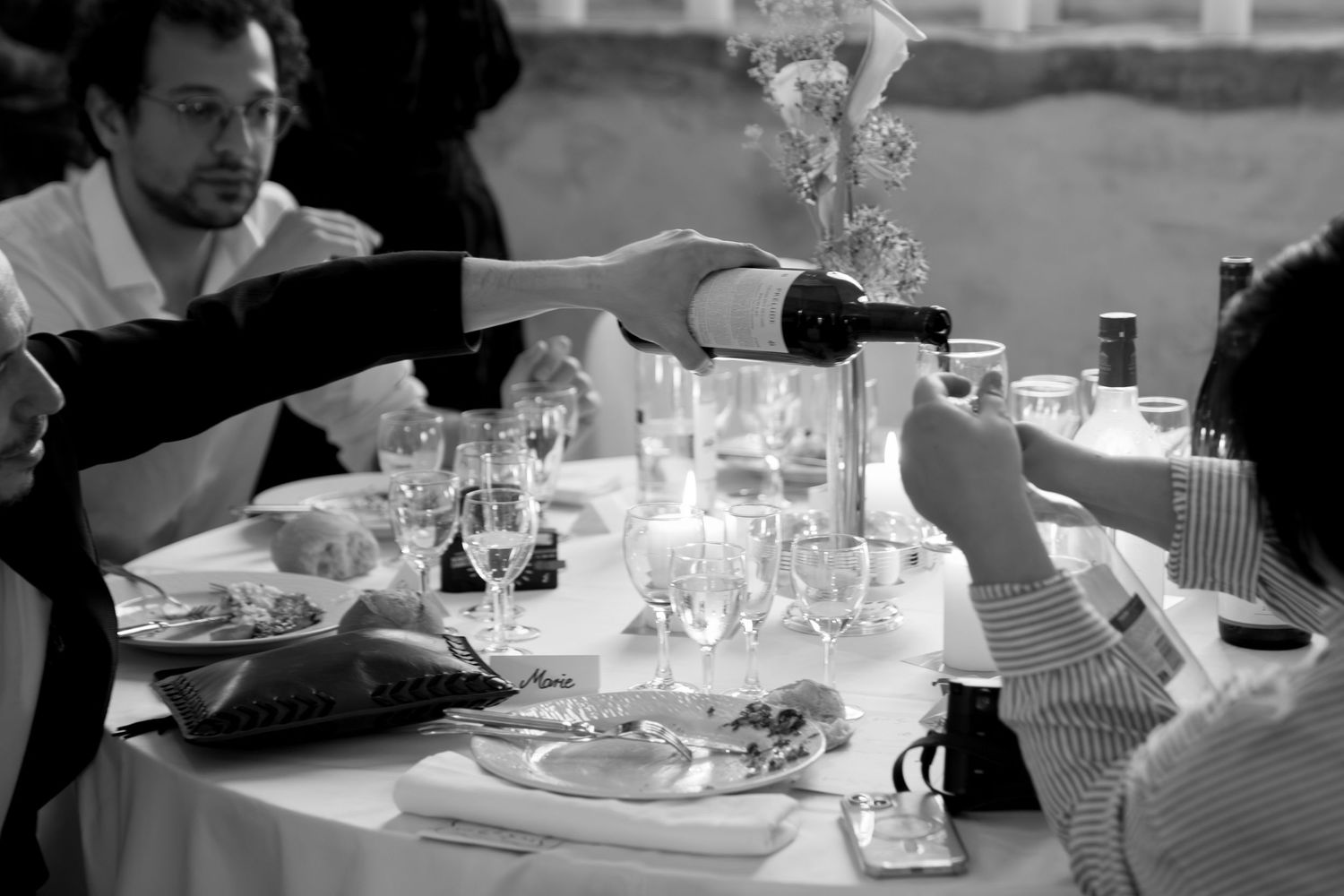 Wedding reception table settings with wine glasses and place settings captured in moody lighting.
