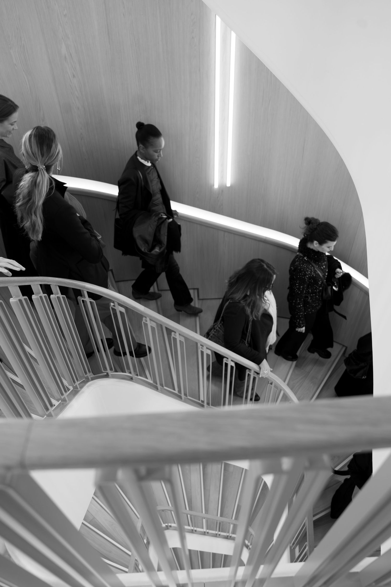 Cinematic black and white event photo of guests on spiral staircase at Paris venue, editorial and documentary style.