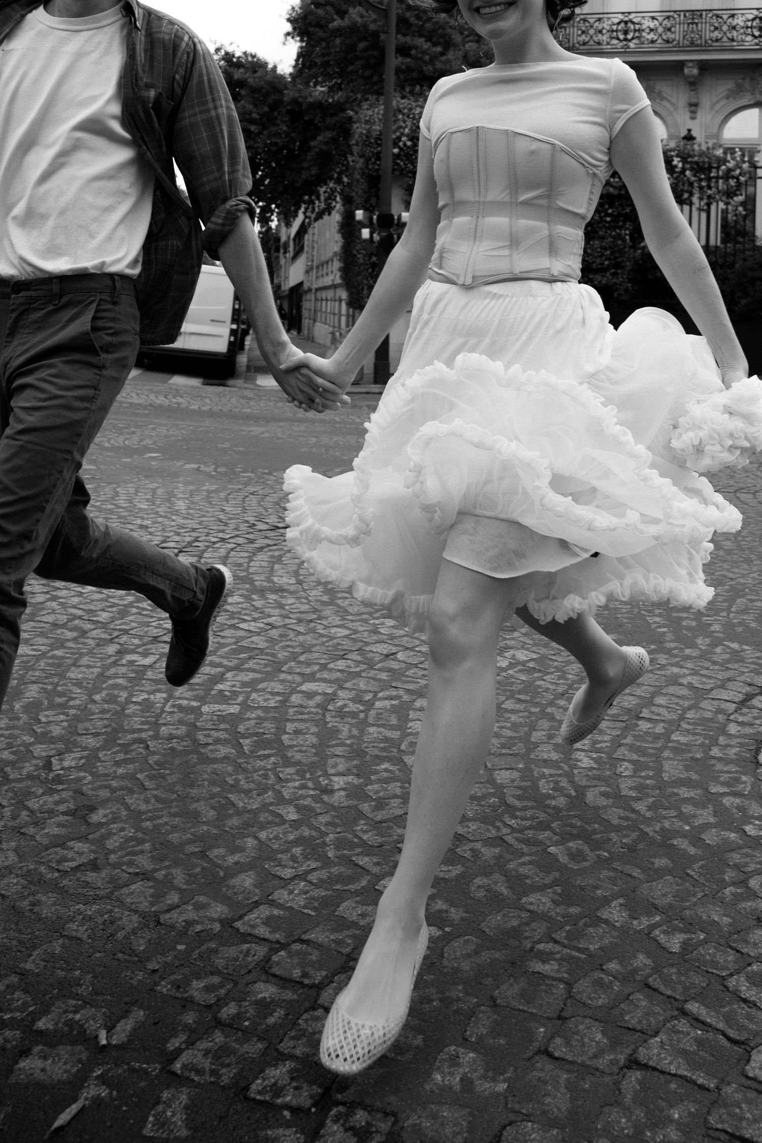 Dynamic black and white sequence showing a couple running across a cobblestone pavement in Paris.
