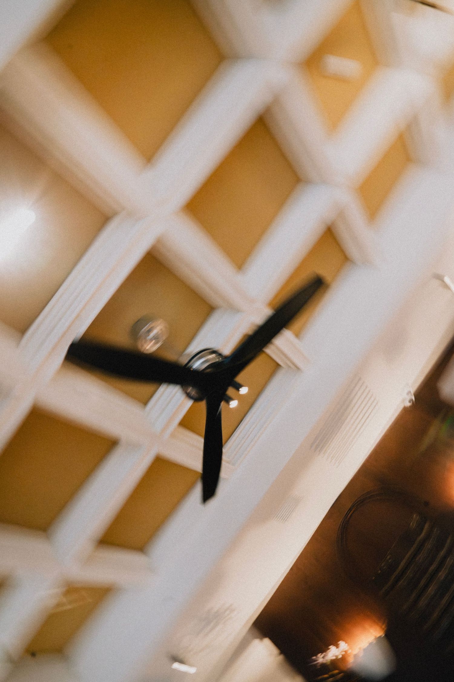 Abstract view of white coffered ceiling with dramatic lighting and architectural details.