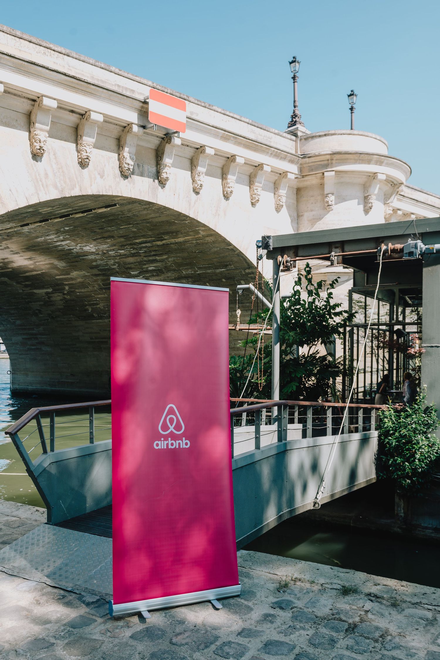 Pink Airbnb banner display stands against white architectural backdrop in multiple outdoor settings.