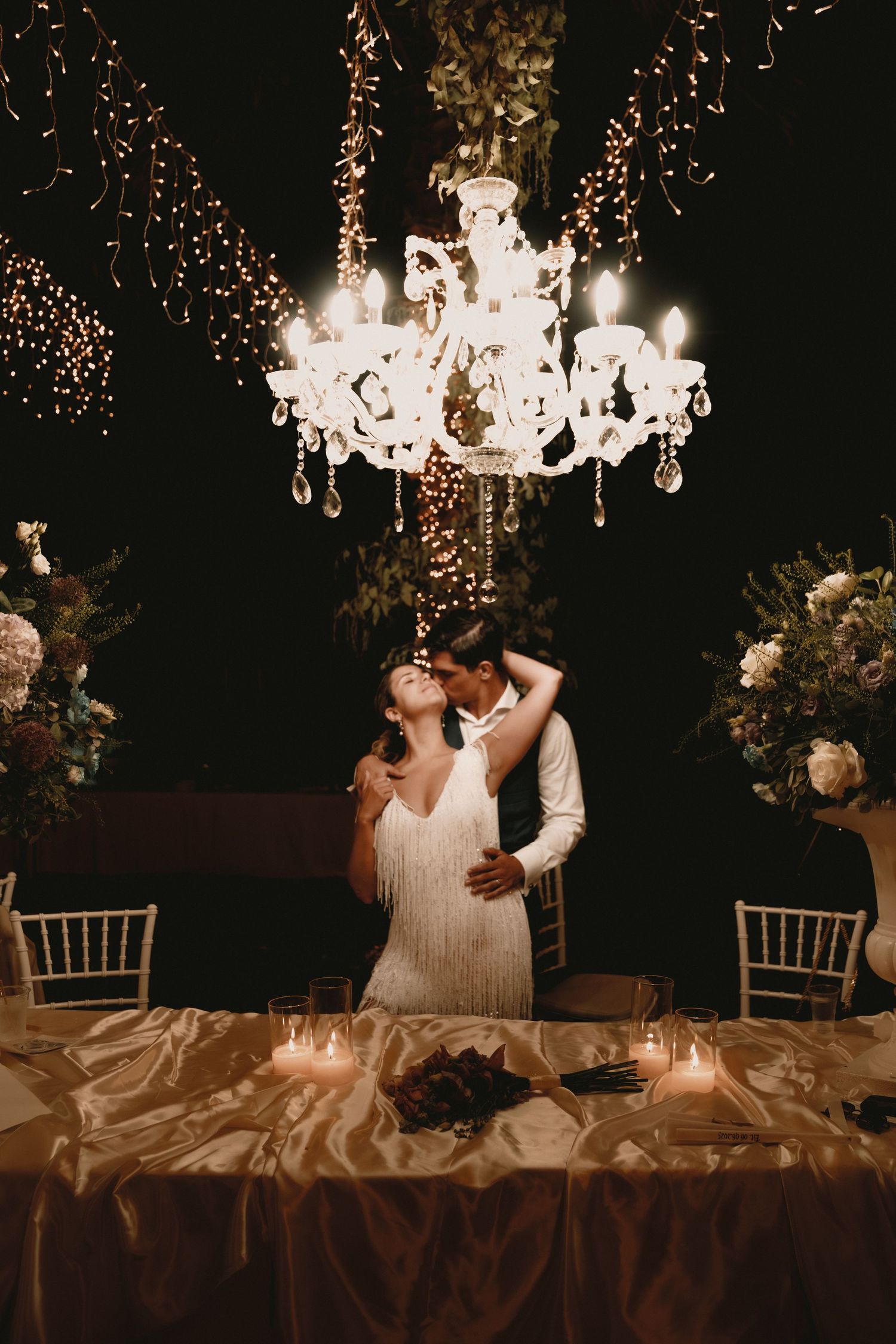 Romantic evening reception scene with crystal chandeliers and twinkling lights creating an intimate atmosphere.