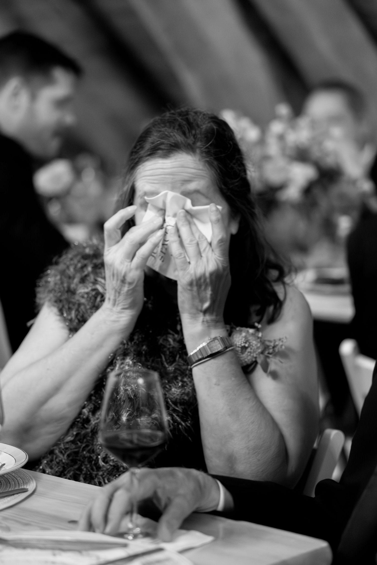 Wedding guest wiping away tears during dinner speech, candid emotional moment at château wedding near Paris by Studio Reverie.