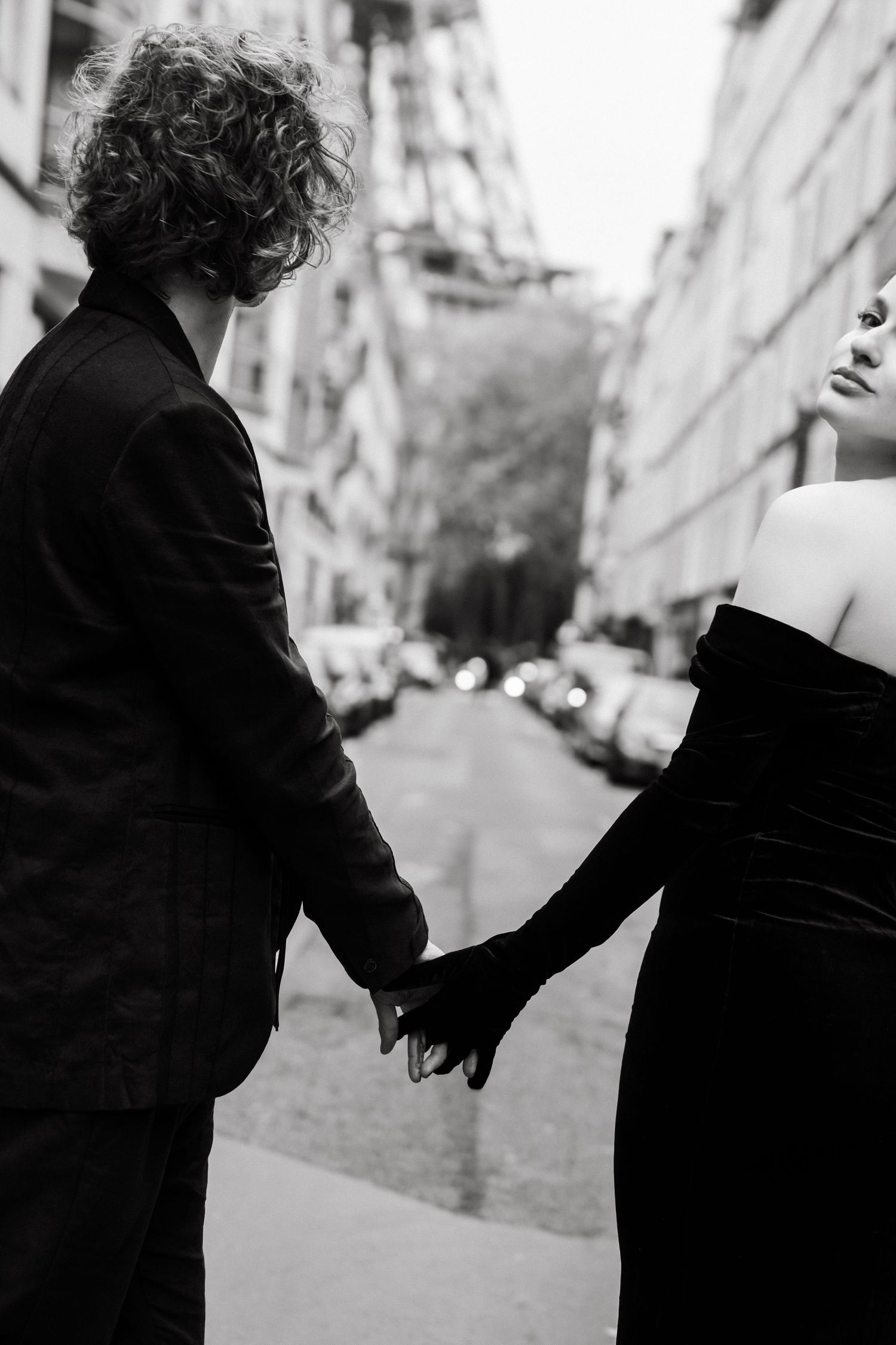 Editorial couple holding hands in Paris near the Eiffel Tower, fashion-inspired black and white photography by Studio Reverie.