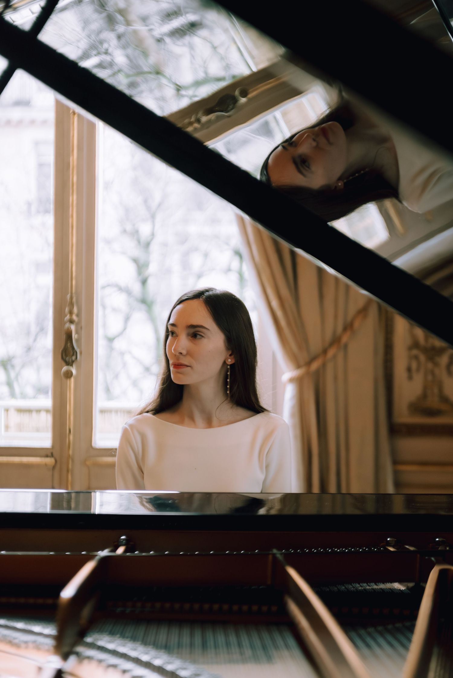 Soft natural light streams through windows in an elegant room with a grand piano.