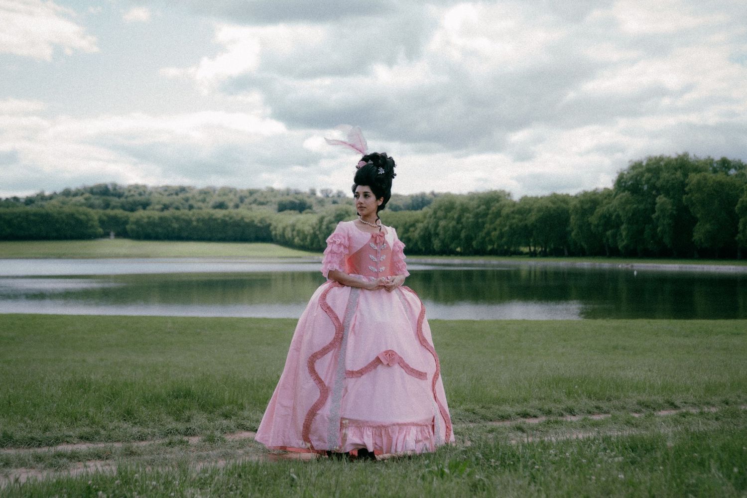 A series of landscape photos showing someone in a flowing pink dress walking through scenic natural settings near a lake.