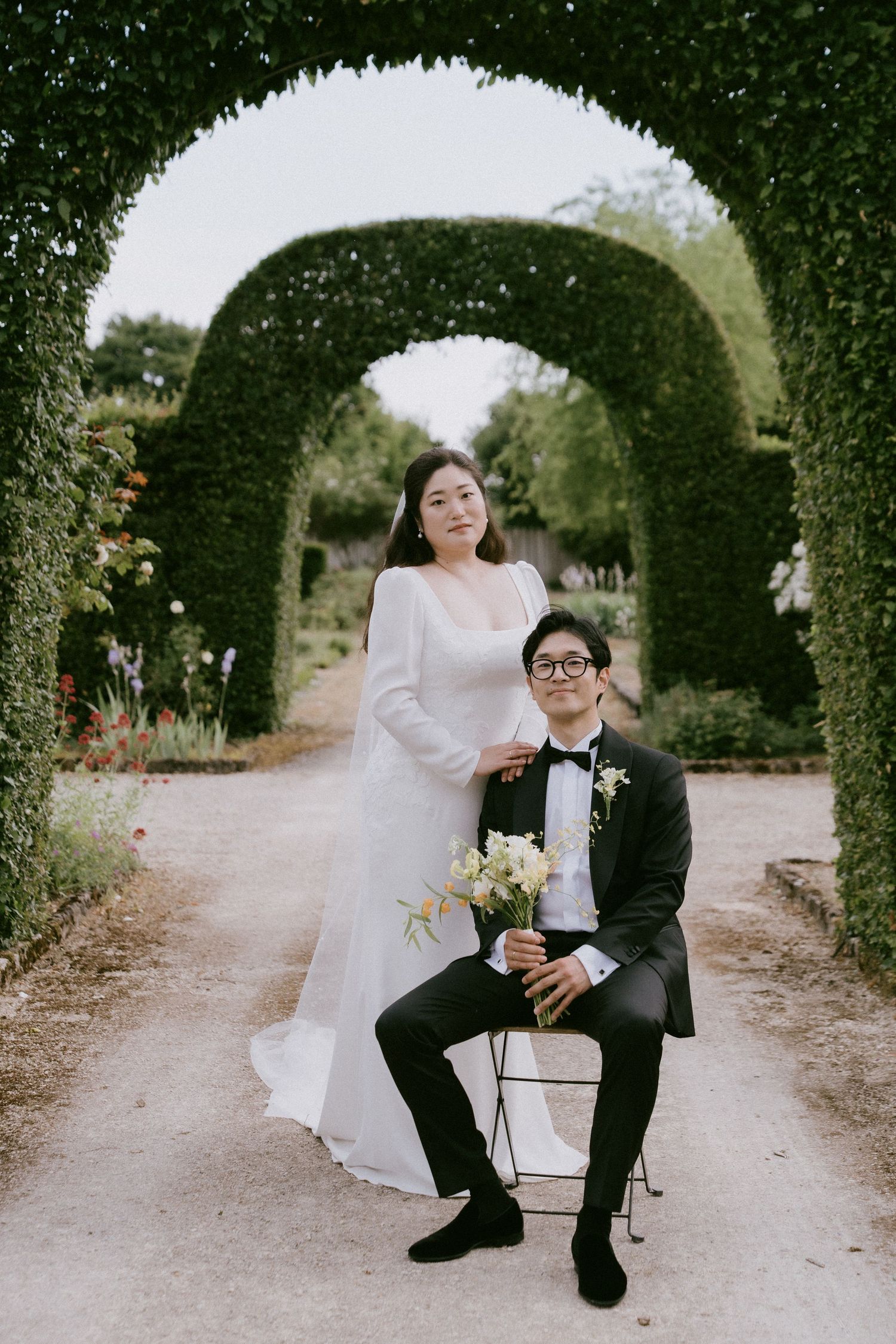 A couple poses under a green garden archway during their wedding photoshoot.